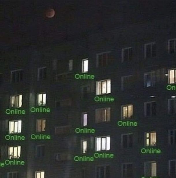 Dark apartment building at night with green Online status indicators on every lit window, representing all the unsecured devices connected to the internet