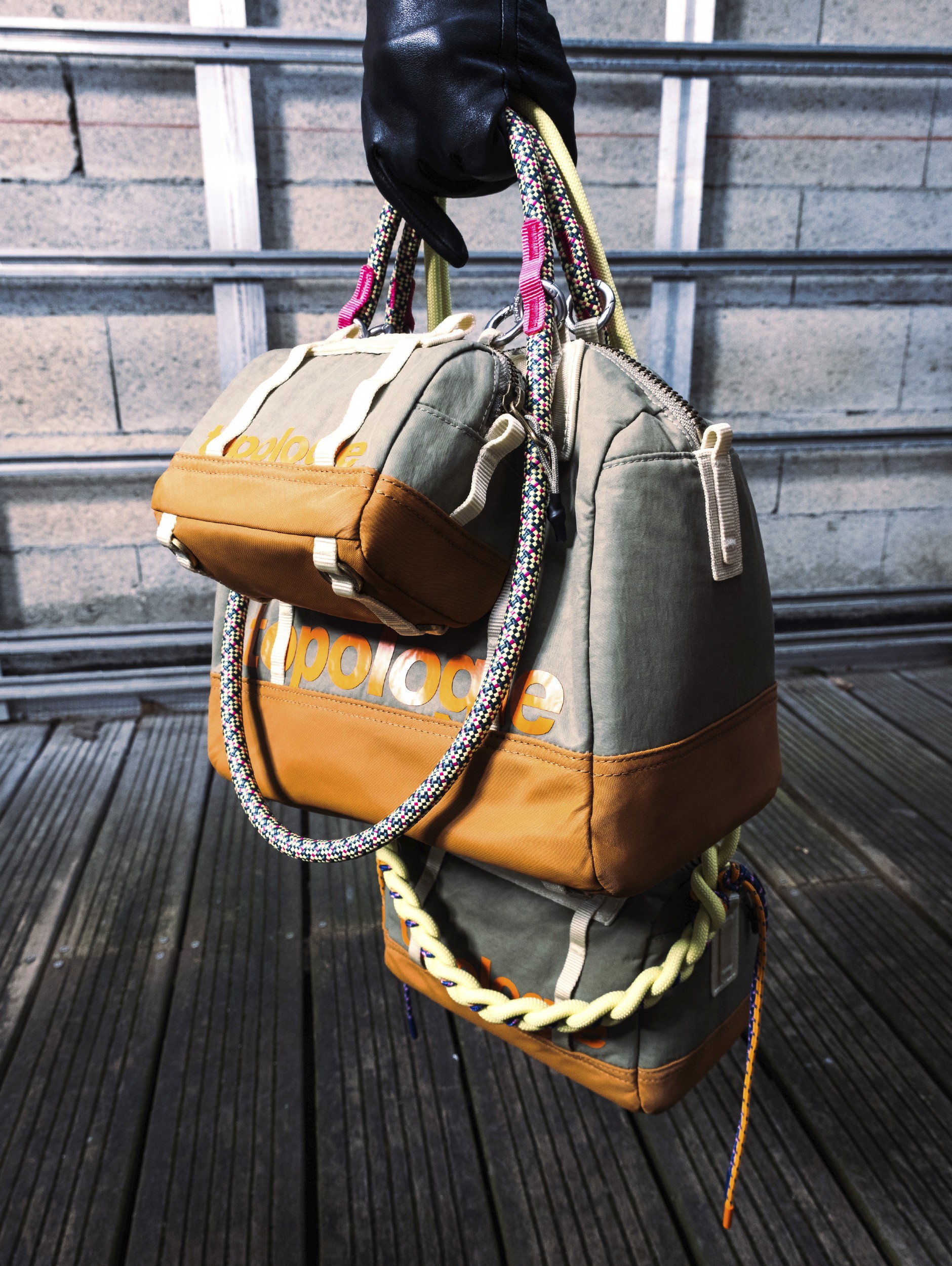 Gros plan sur 3 sacs gris et orange de taille différente de la marque apparente Topologie