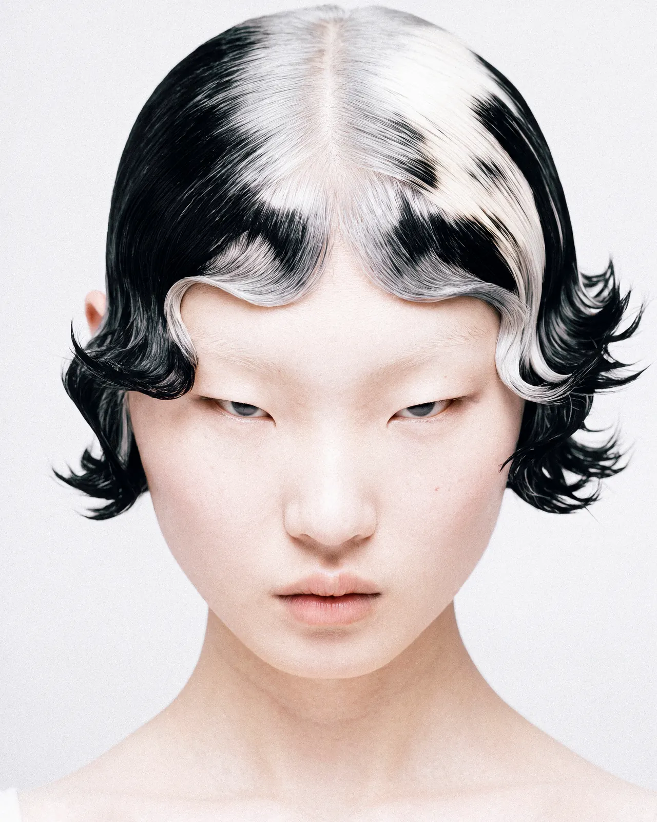 Close-up portrait with glossy black-and-white finger waves against a pale background.