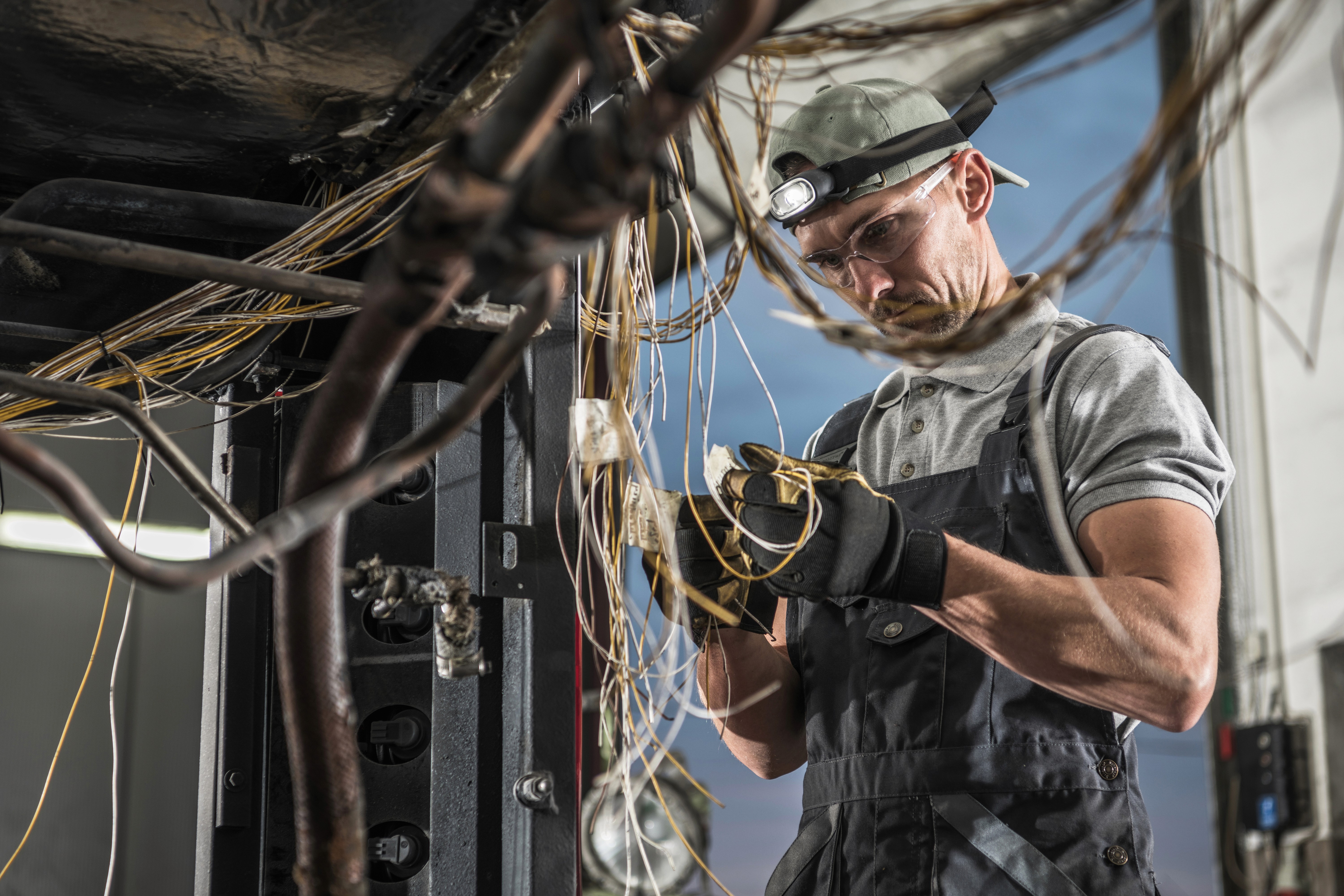 A electrician in blue overalls working on wiring