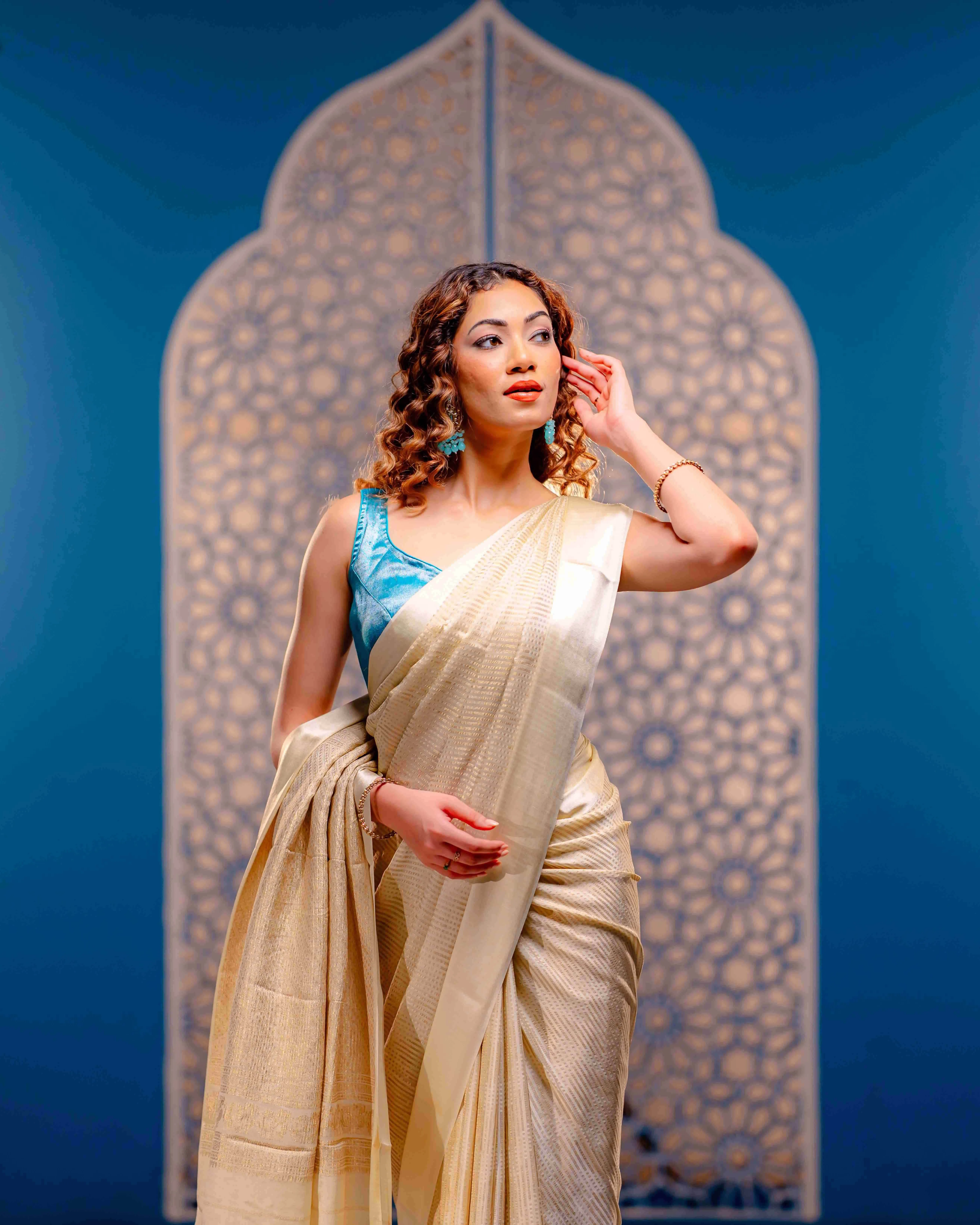 A woman wearing an ivory cream saree, radiating subtle sophistication and refined traditional beauty.