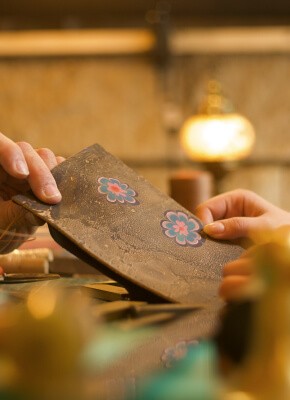 A close-up of hands holding a piece of leather with decorative floral patterns during a leather crafting workshop in Istanbul, showcasing traditional techniques.