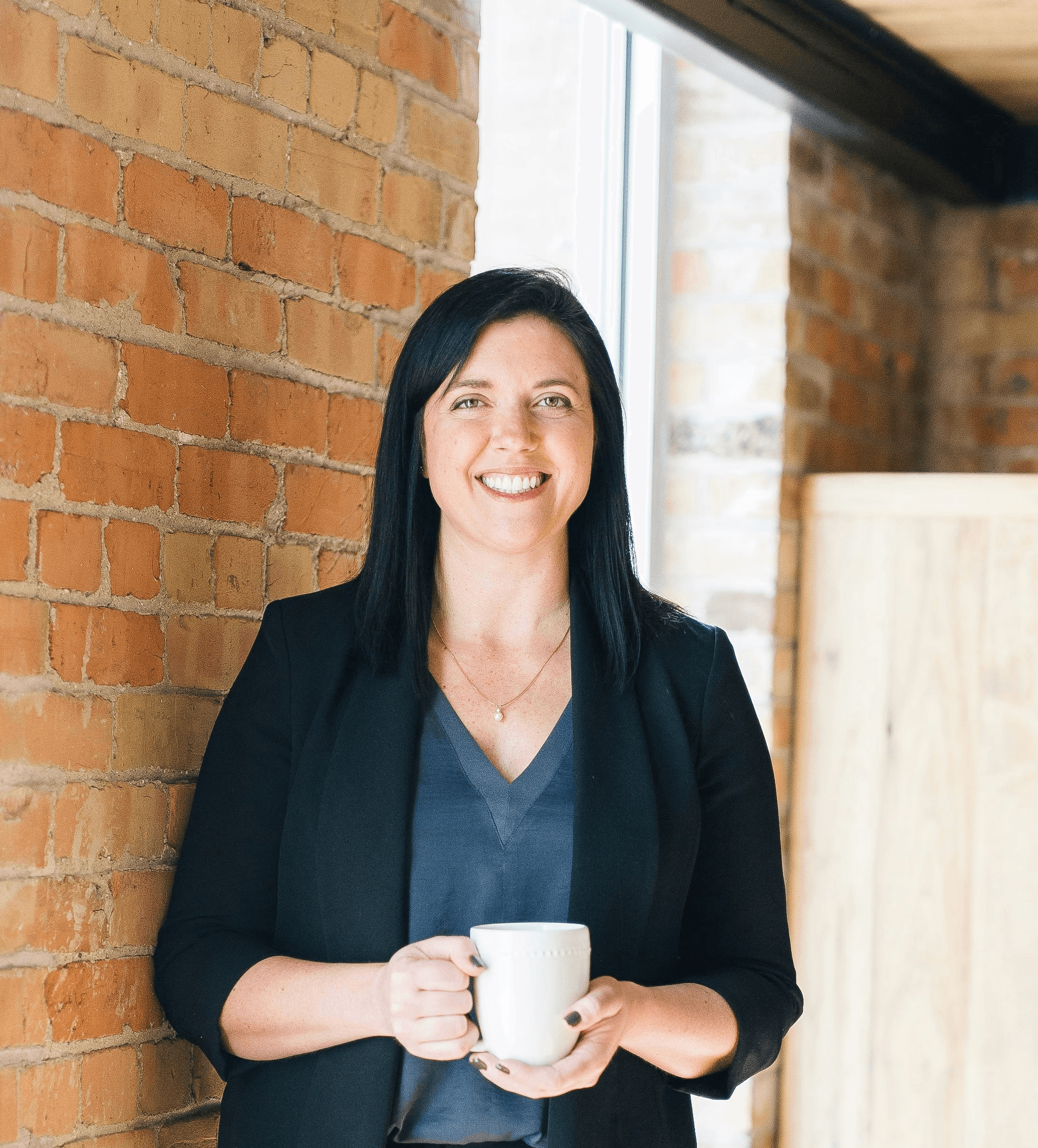 woman standing by wall holding mug
