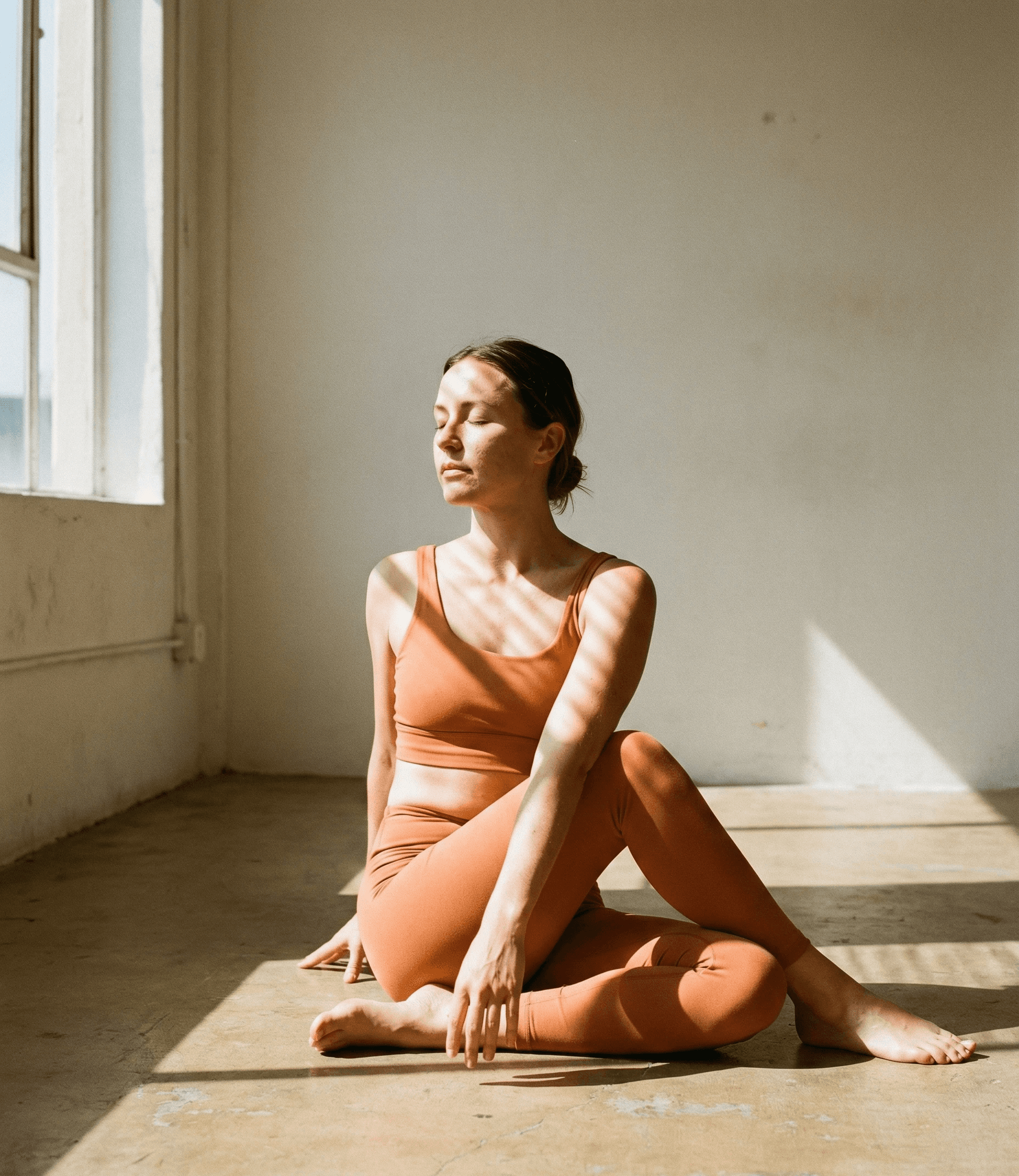 A person with curly hair sits at a desk, working on a laptop in a cozy, well-lit environment.