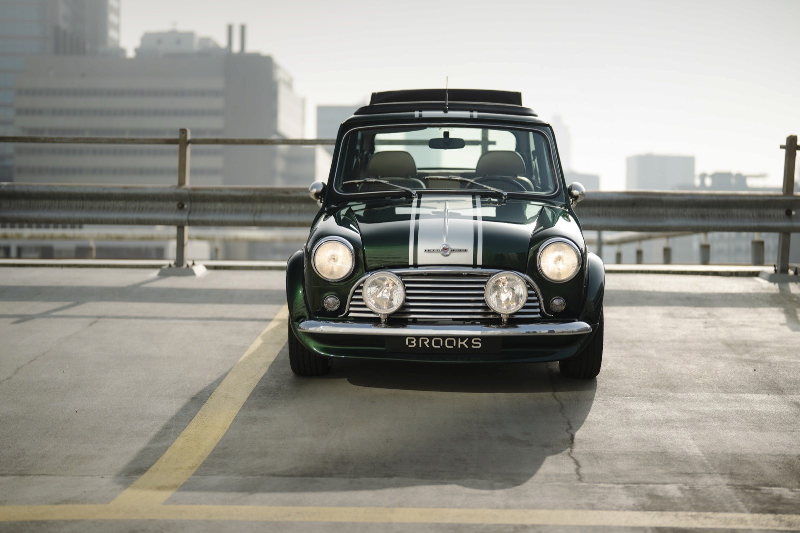 A classic black car parked on a rooftop with a city skyline in the background.