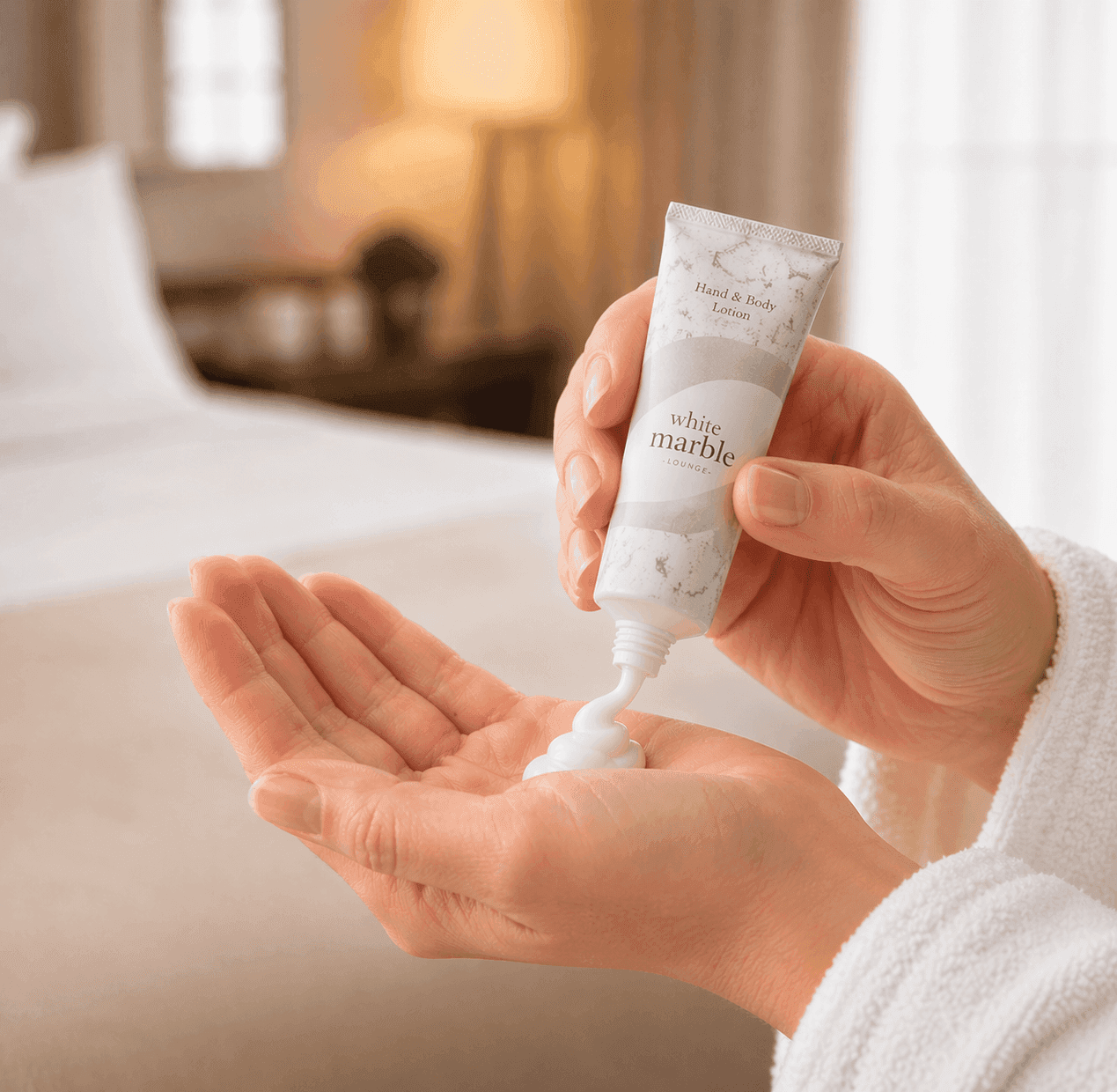 Transmacro Dial White Marble hand and body lotion being applied on hands in a hotel room setting with soft lighting and a clean minimal background