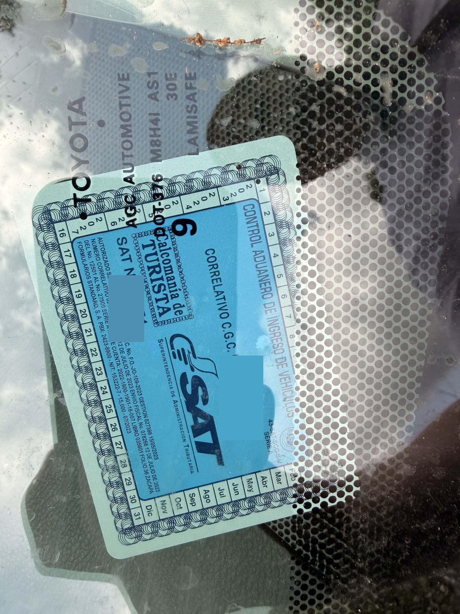 A Guatemalan SAT tourist vehicle permit sticker on the inside of a windshield.