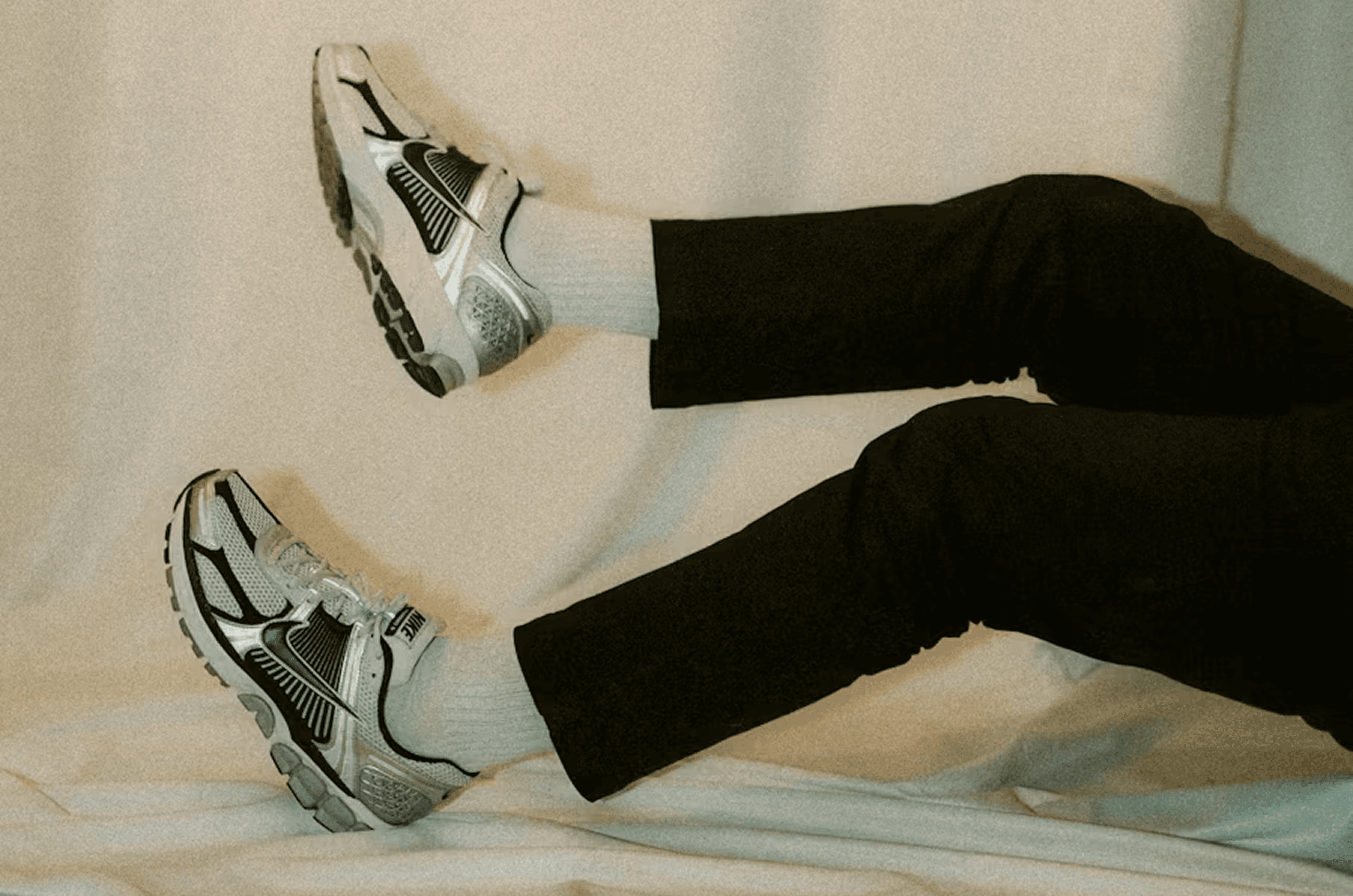 Close-up of a person’s legs resting on a light surface, wearing black trousers, white socks, and running shoes — representing modern work-life flexibility, experimentation, and a practical LinkedIn advertising playbook for driving B2B growth in a real-world context.