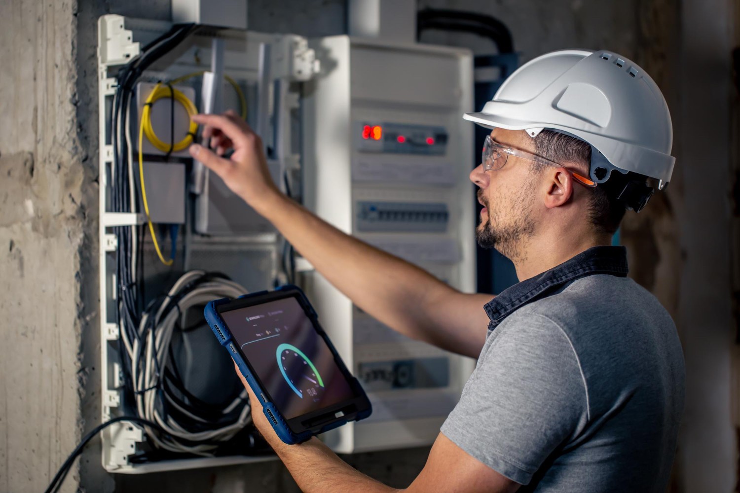 Worker inspecting equipment with safety gear under bright industrial lighting.