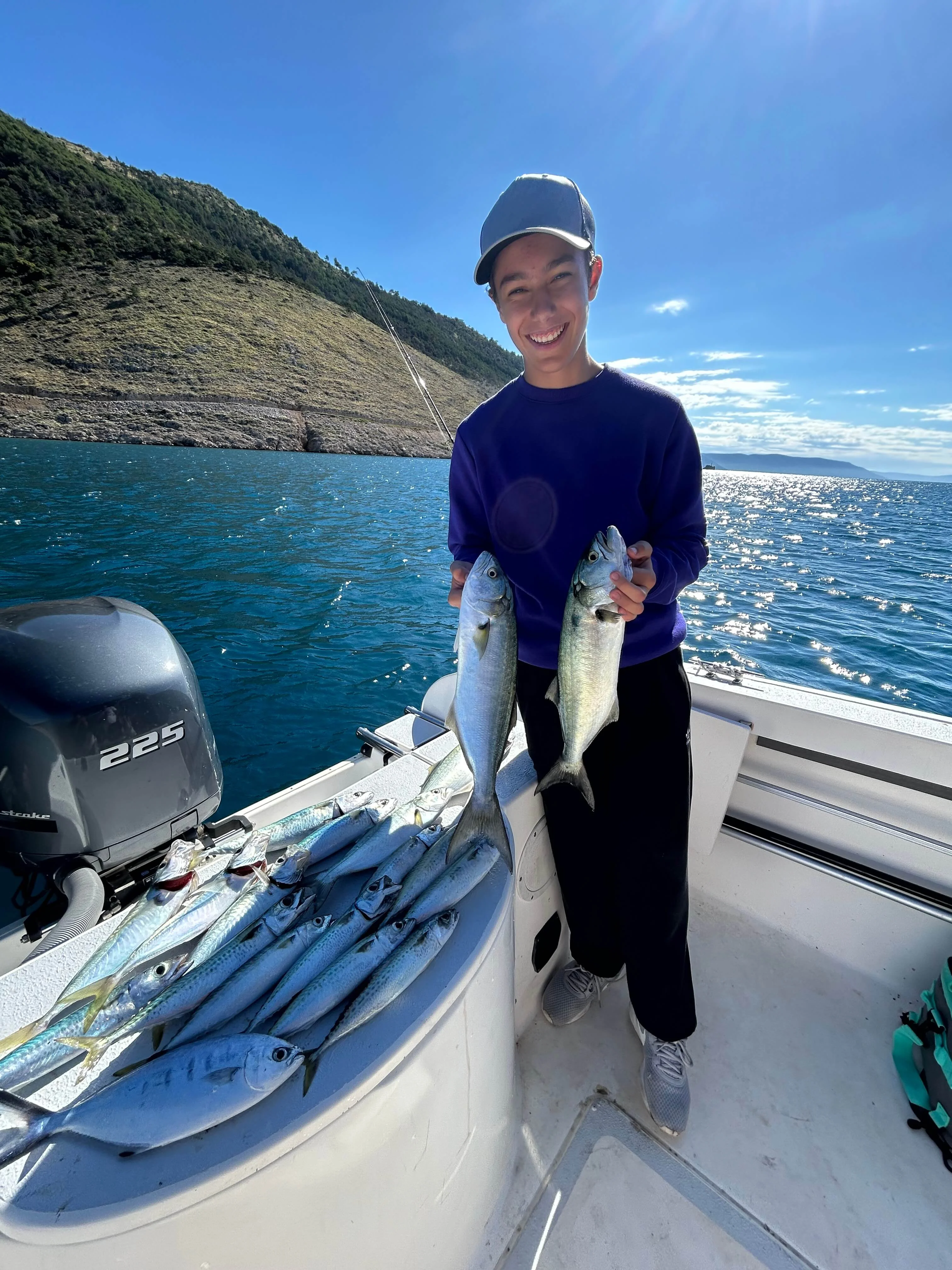 Child having fun catching fish during a family fishing trip on the Adriatic Sea.