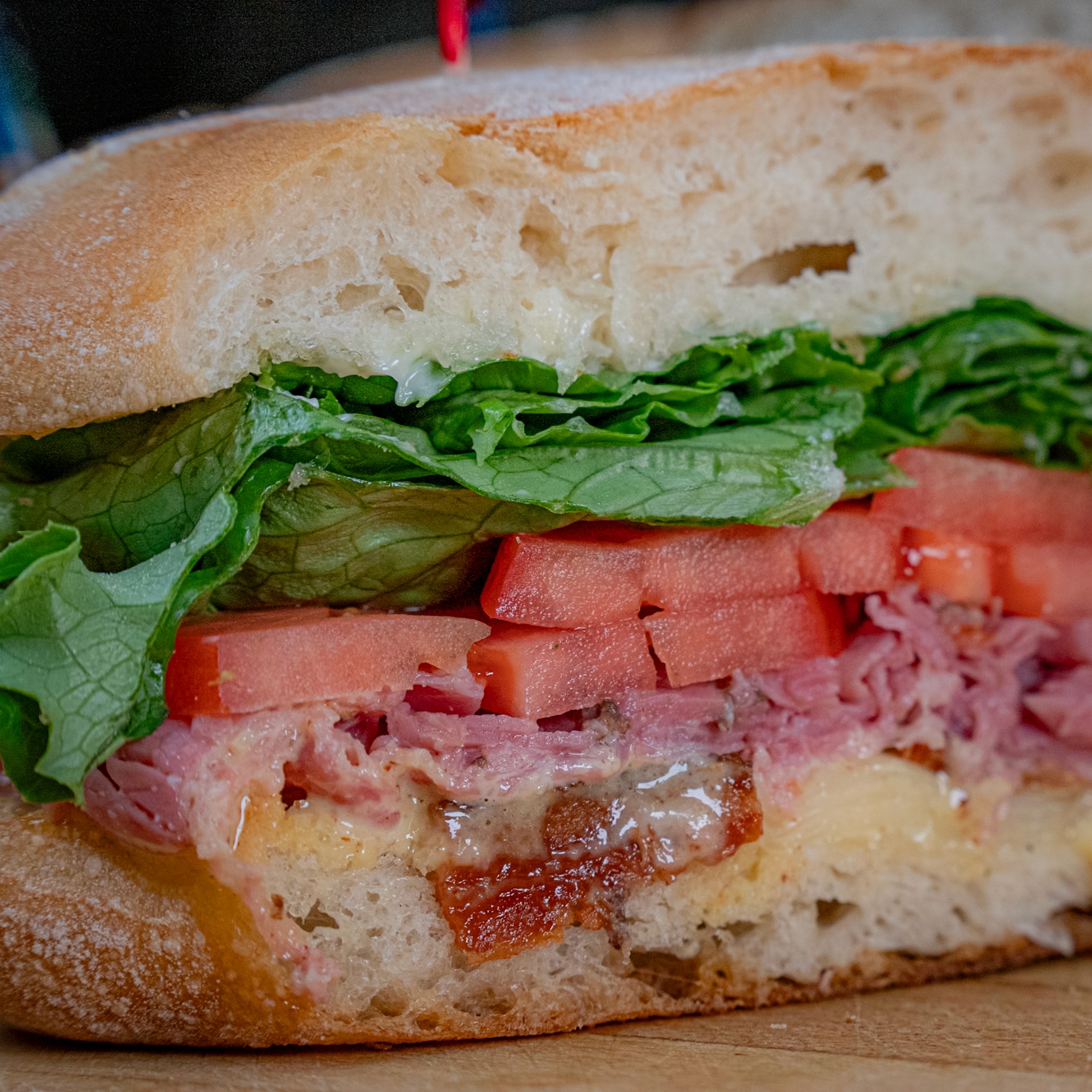 Italian deli sandwich with salami, provolone, lettuce and tomato on a ciabatta roll