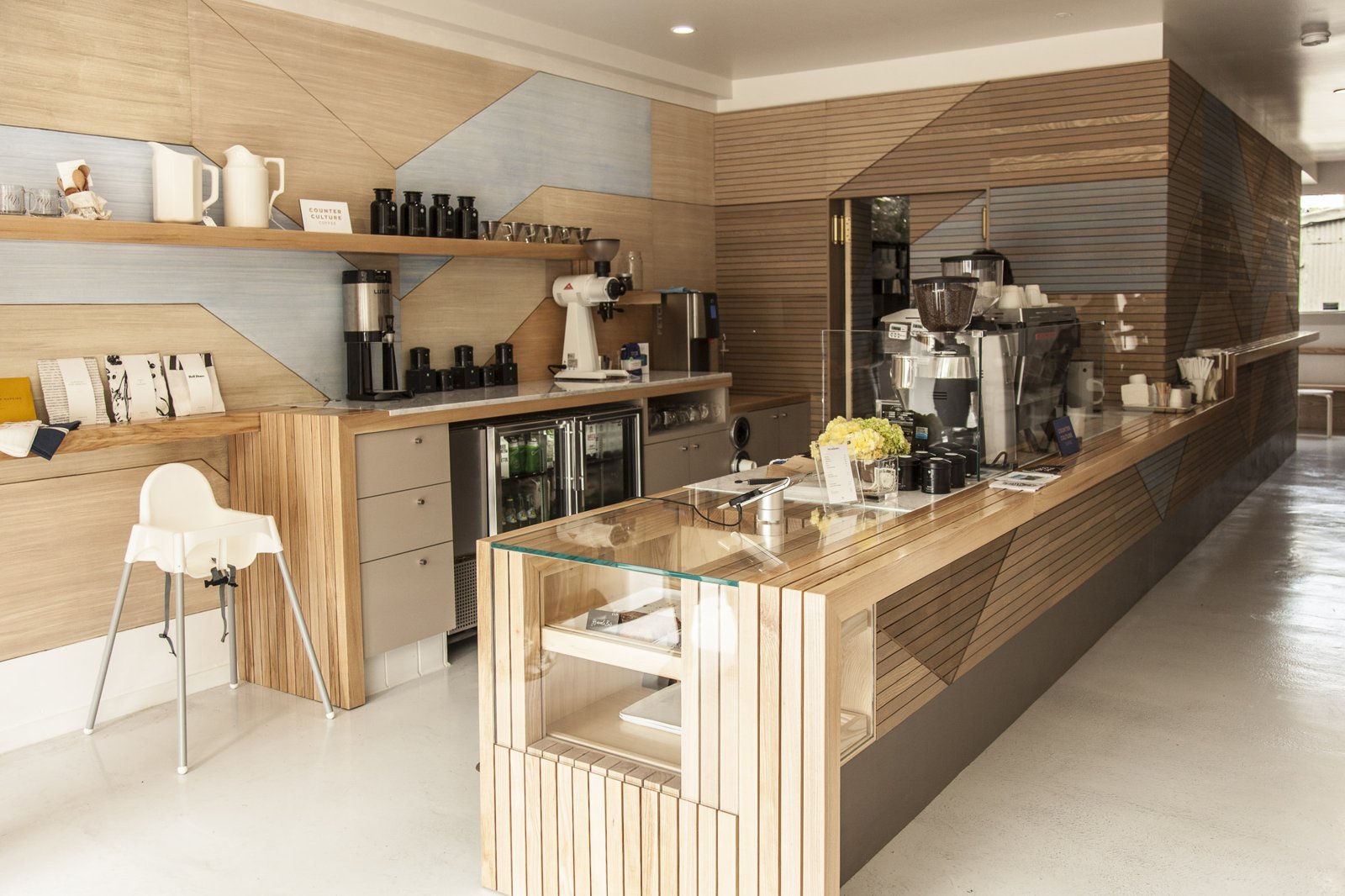 Room view across the coffee counter and geometric timber walls.