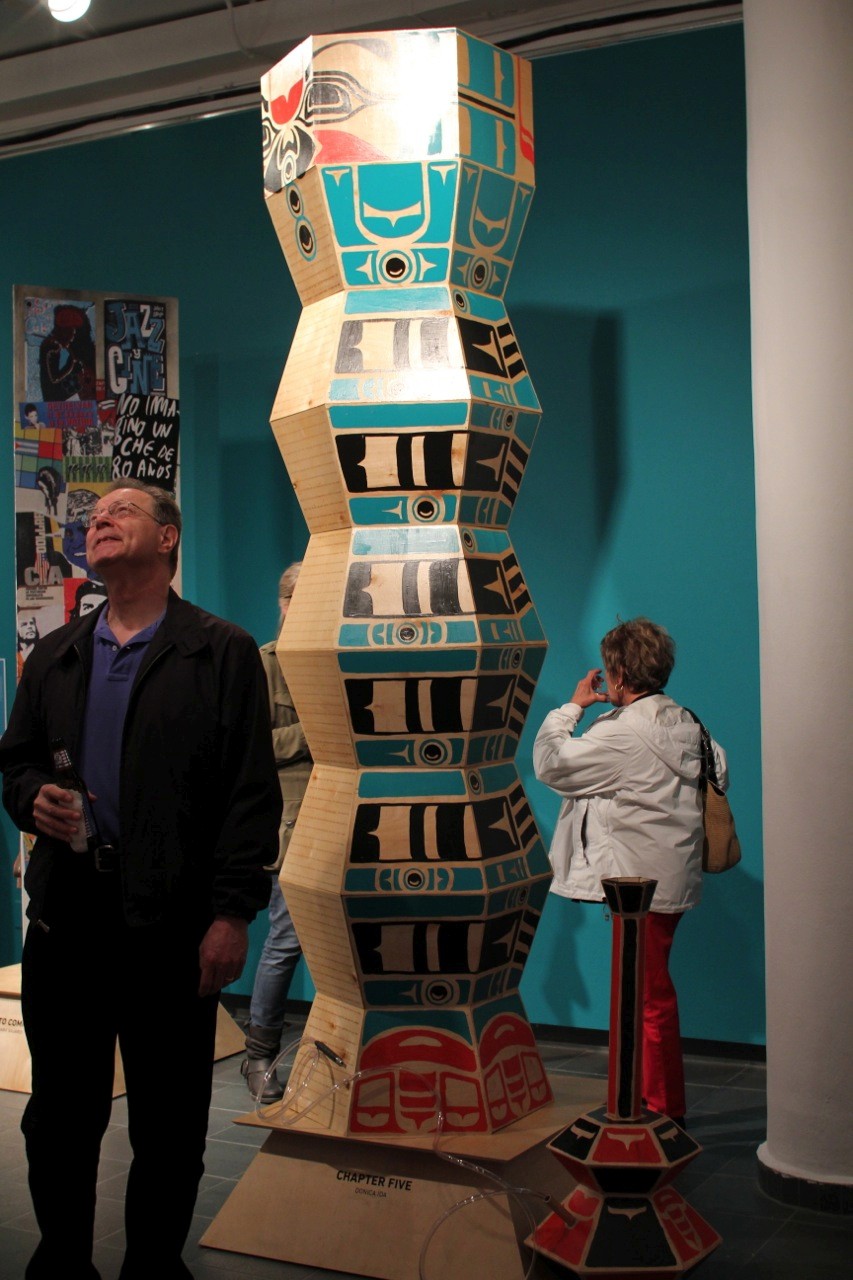 A photo of a hexagonal shaped tower made from painted cardboard that looks like a totem.