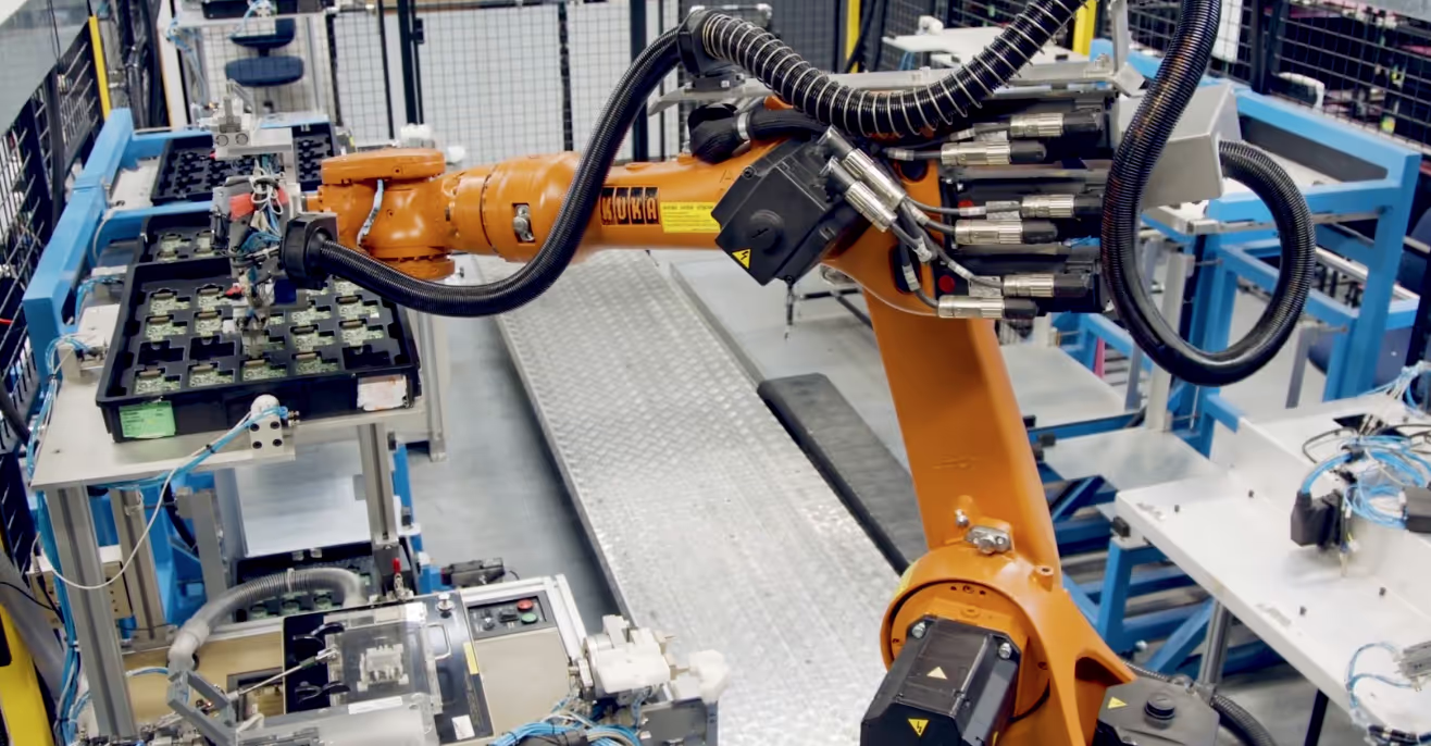 An orange industrial robotic arm working over a production line inside a factory