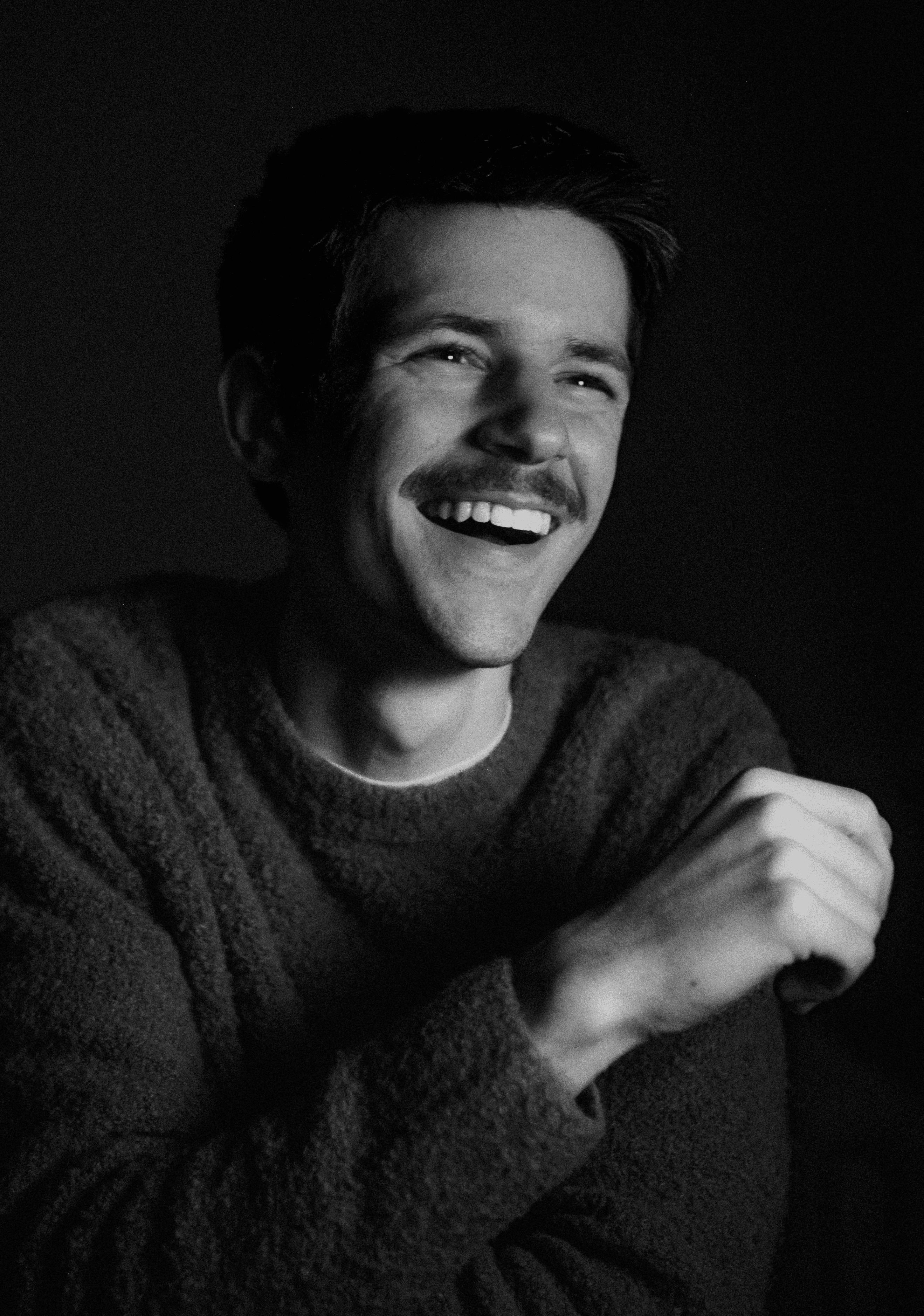 Portrait of a laughing person with curly hair wearing a white shirt