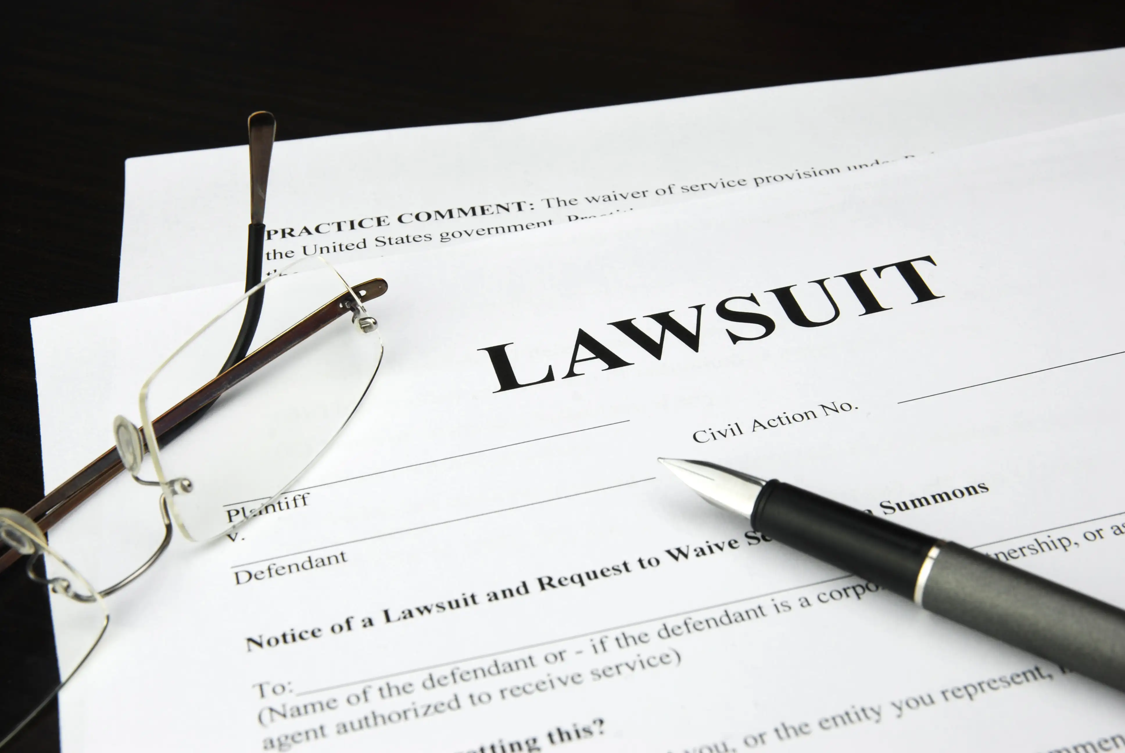 Civil lawsuit court documents, pen, and eyeglasses representing damages, back pay, interest, and attorney's fees recoverable under California Labor Code section 1194