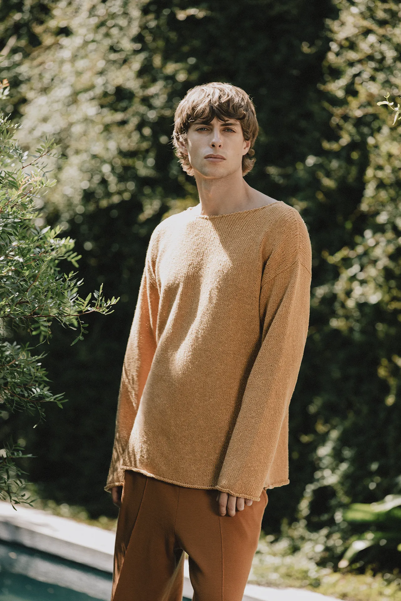 Annapurna SS26 collection men's mustard yellow boat-neck knit sweater with raw hem details.