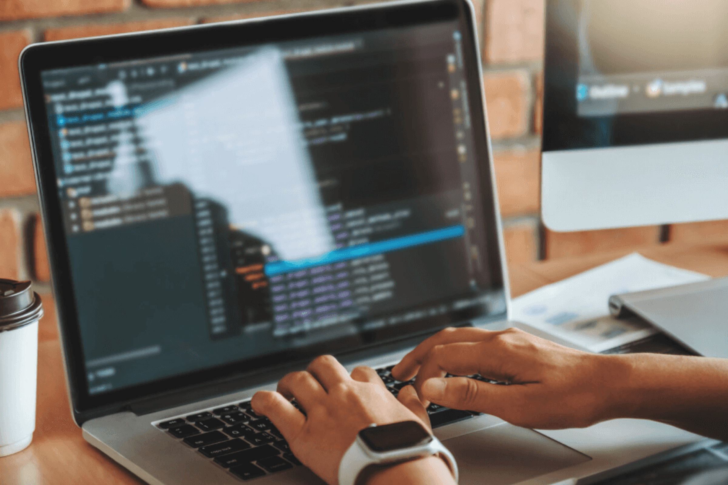 Someone typing on an open laptop displaying a code editor