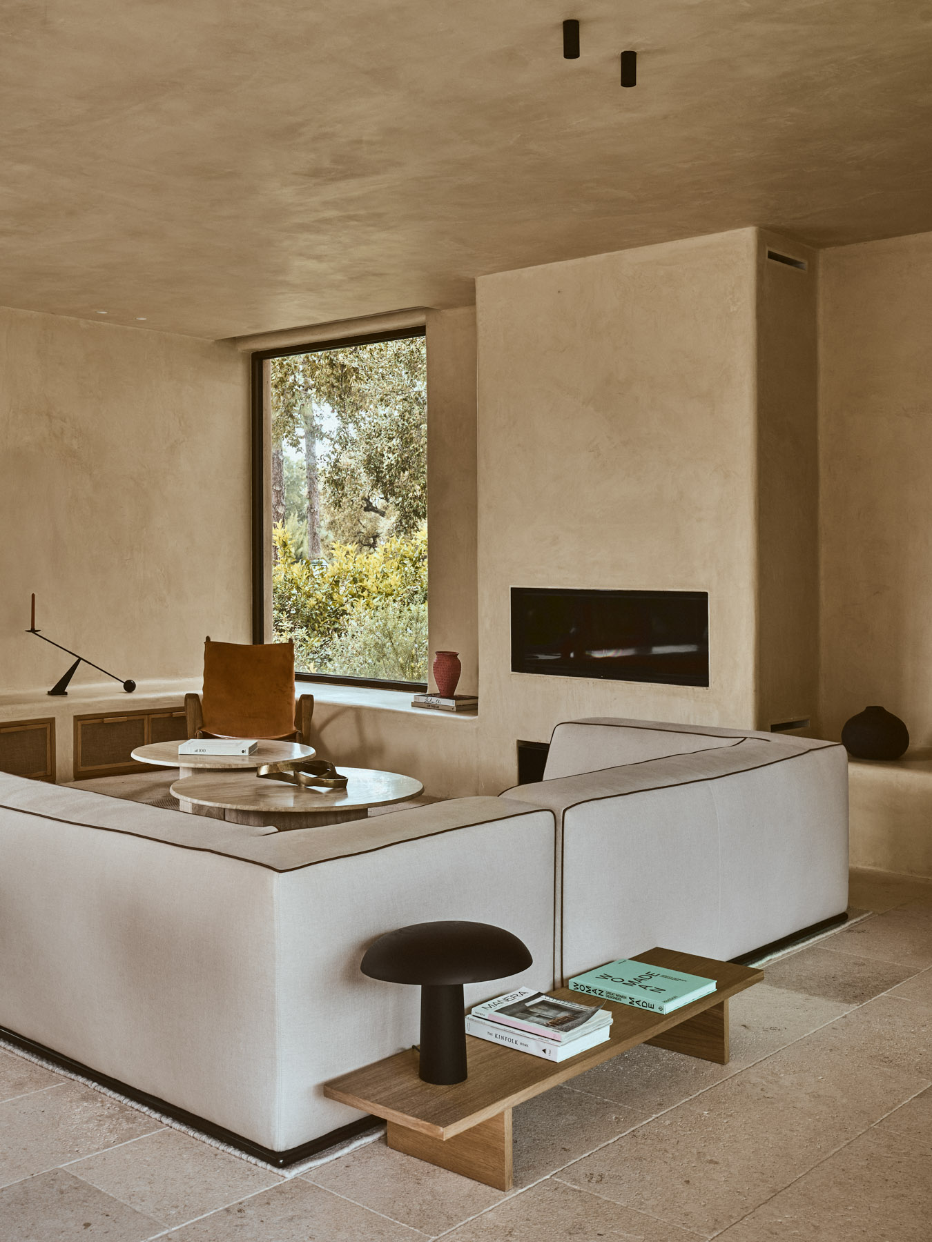 Living room with fireplace, bespoke shelving and large picture window overlooking the pine landscape of Sotogrande.