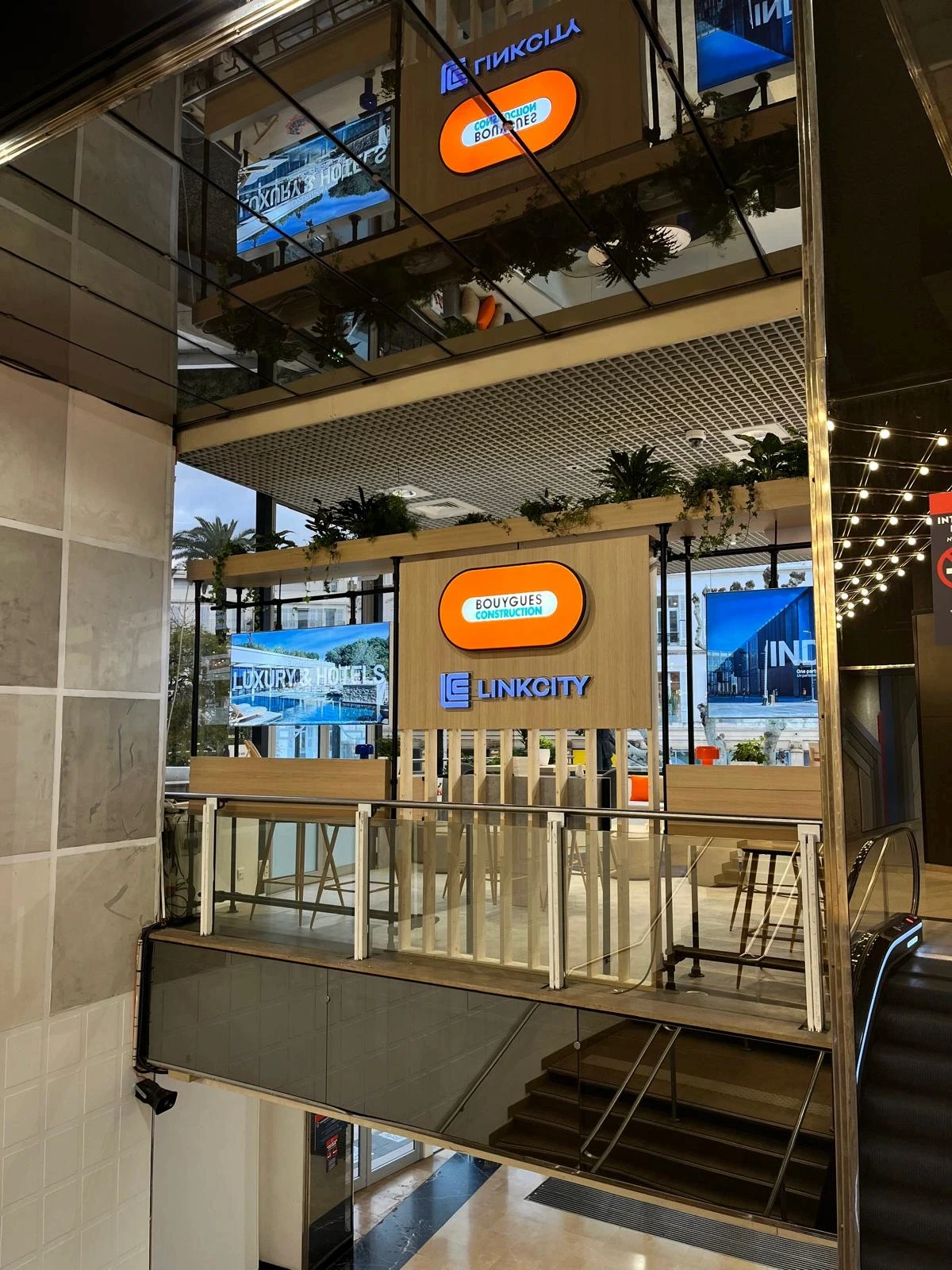 Stand Bouygues Construction & Linkcity conçu et réalisé par Expace au MIPIM Cannes 2026 – espace sur-mesure sur la Croisette avec accueil signature, lounge, écrans projets immobiliers et terrasse végétalisée.