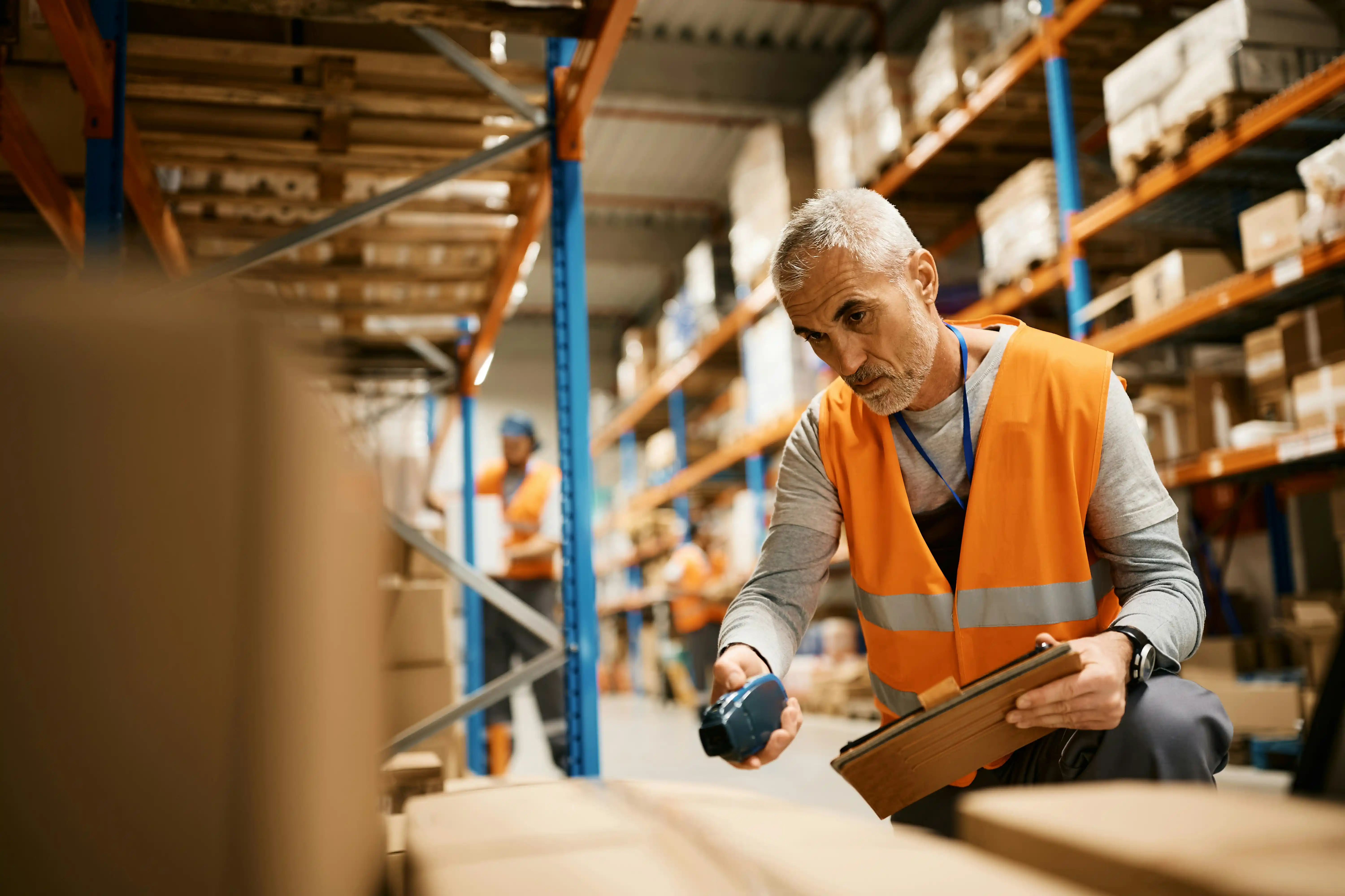 man in orange high-vis jacket scans an item before picking