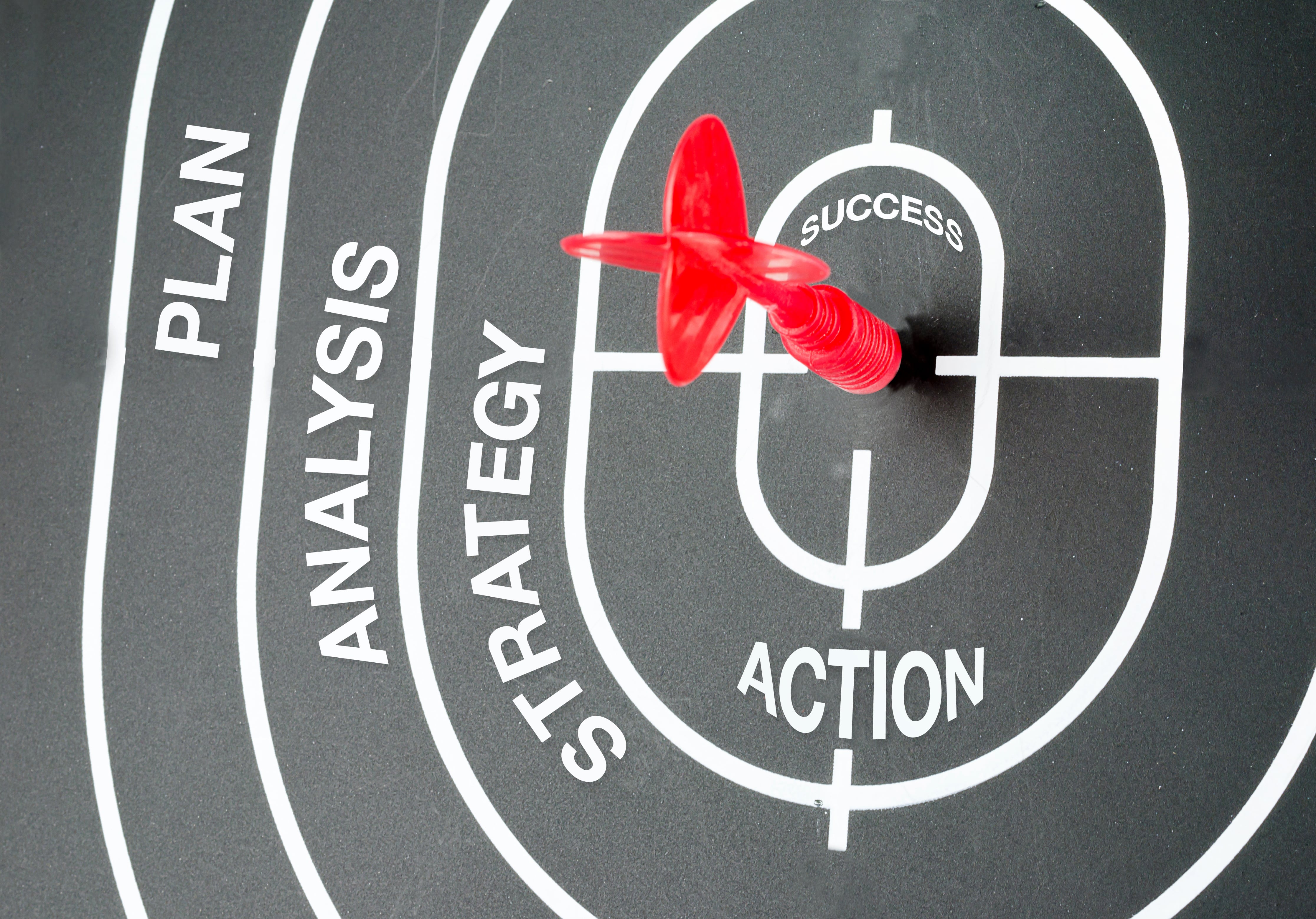 Business planning concept showing steps to success with a red dart hitting the center target labeled 'Success', surrounded by words 'Plan', 'Analysis', 'Strategy', and 'Action'
