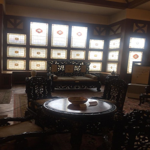 古老的木制家具坐落在一个光线昏暗的房间里，房间内装饰有彩色玻璃窗，展示着复杂的设计。