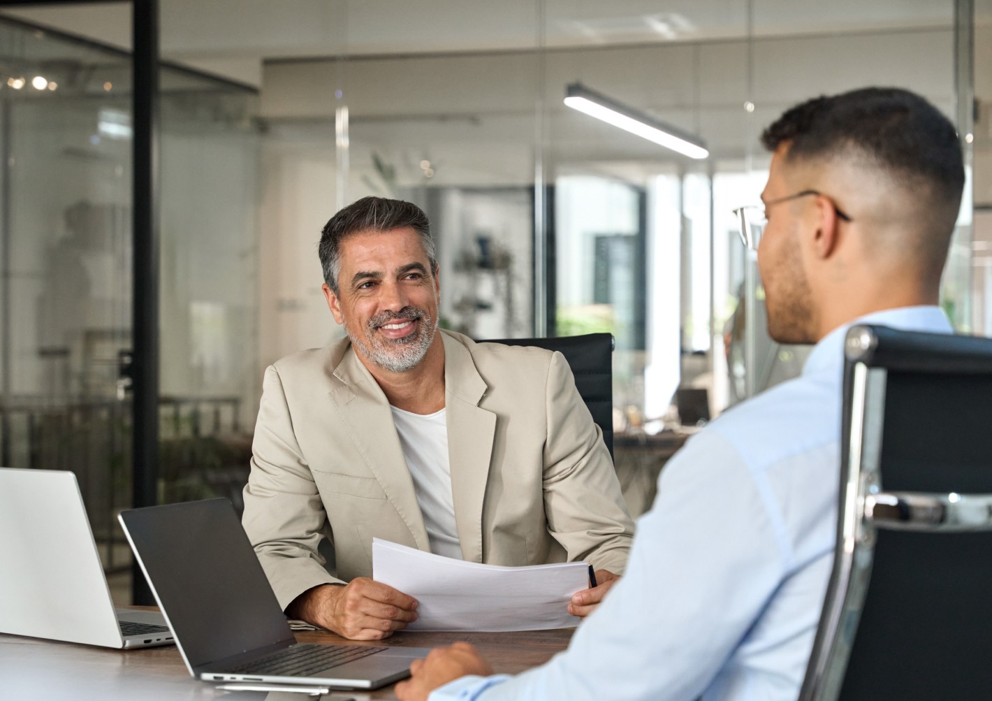 A professional man engaging in a discussion with a document in hand for payroll management. 