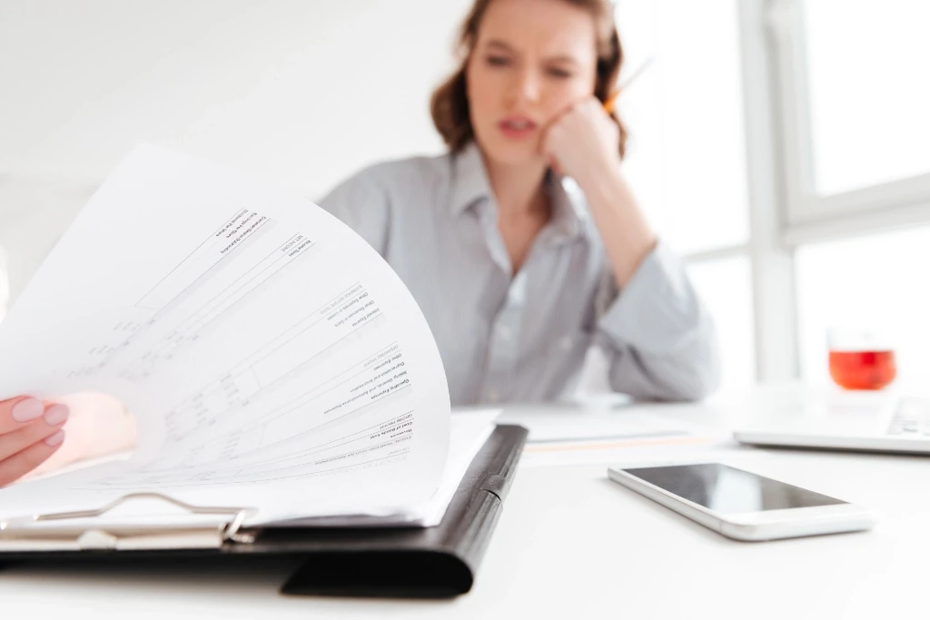 Female flipping through a document on her desk.