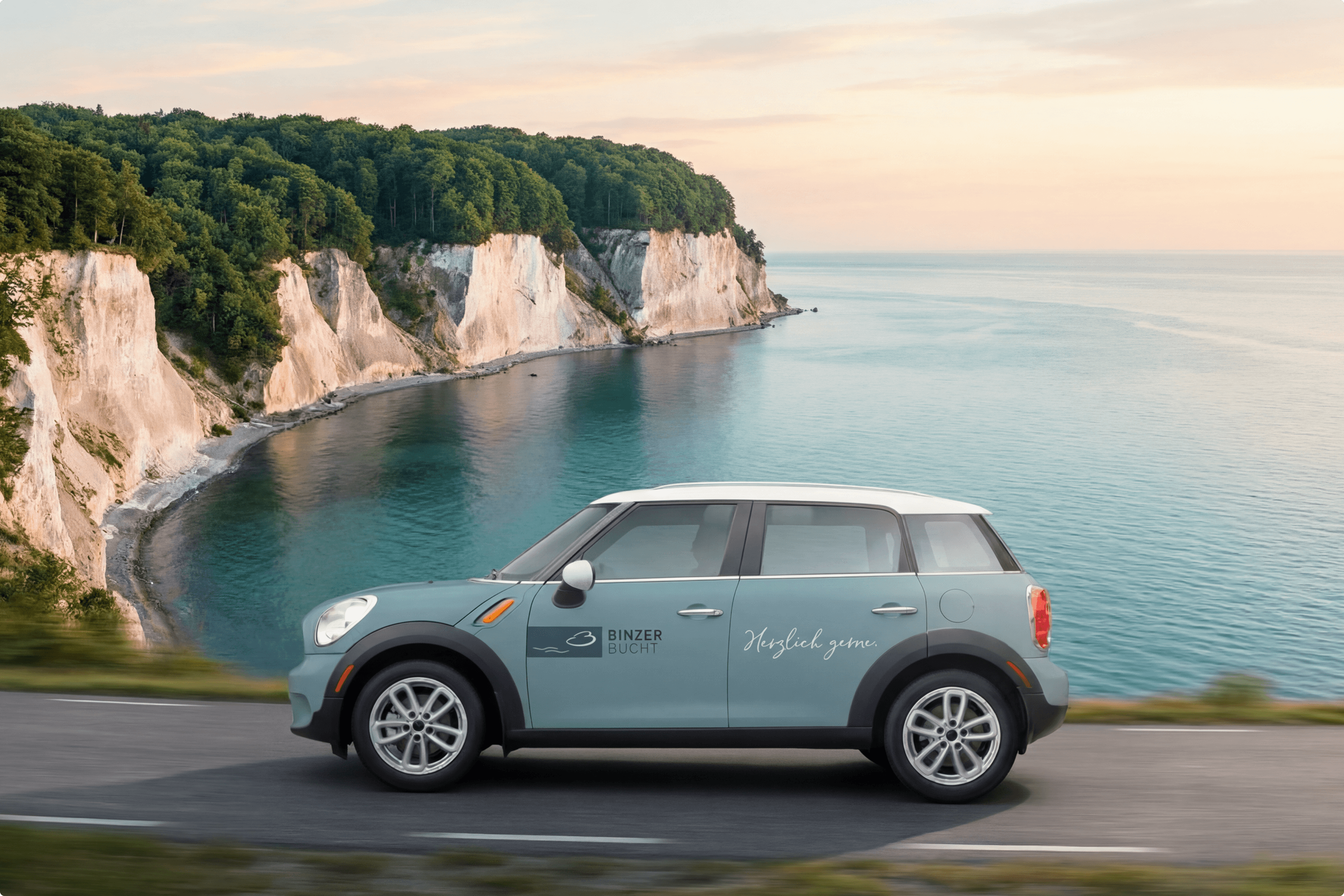 Light blue car driving on road by cliffs and sea