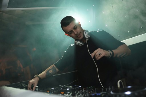 DJ performing live with headphones around his neck, symbolizing the professional music creation capabilities of the Sunora AI Music Generator app