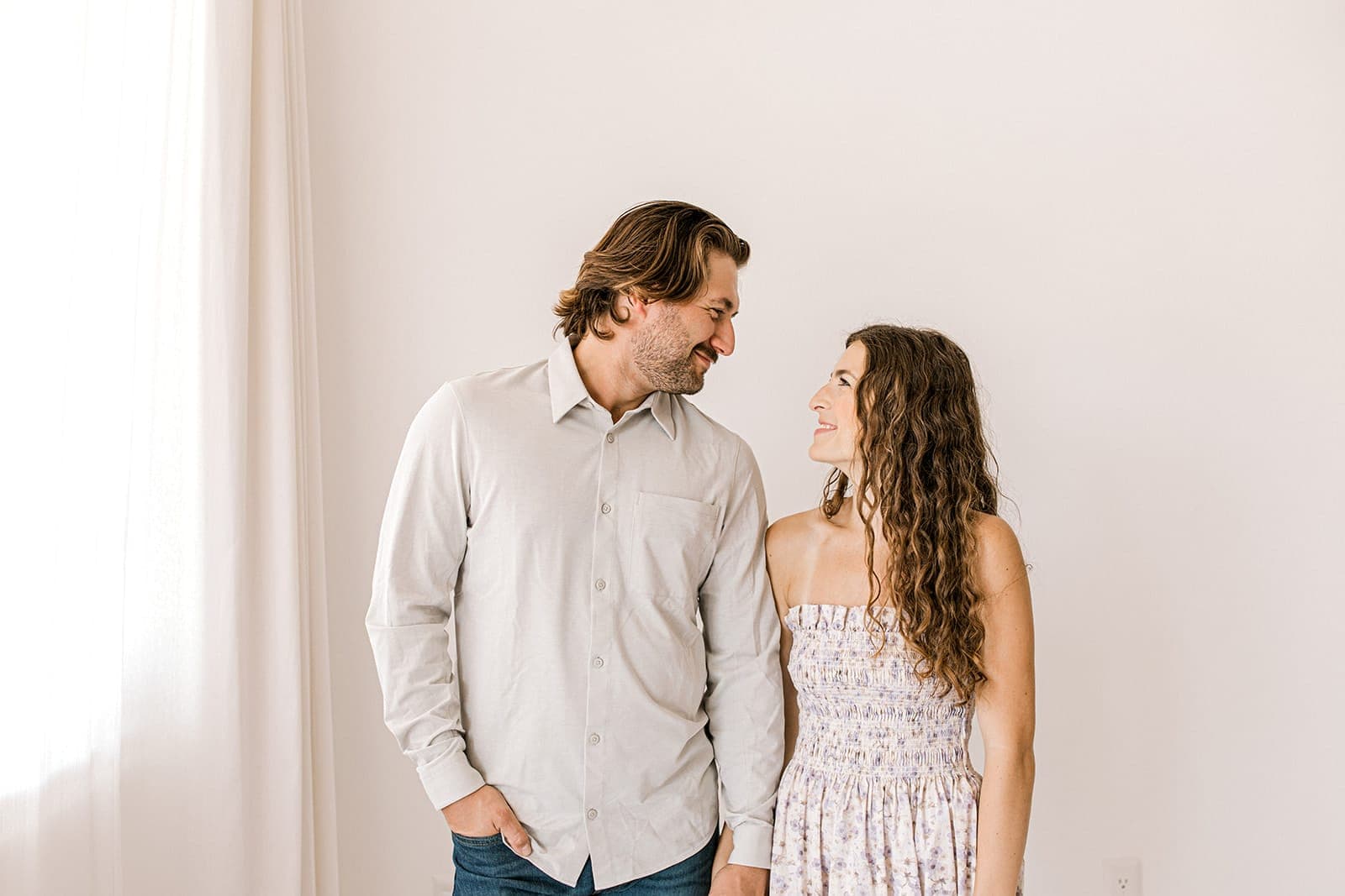 A couple gazing into each other’s eyes while standing in front of a white background at Revelator Studio in Shreveport.