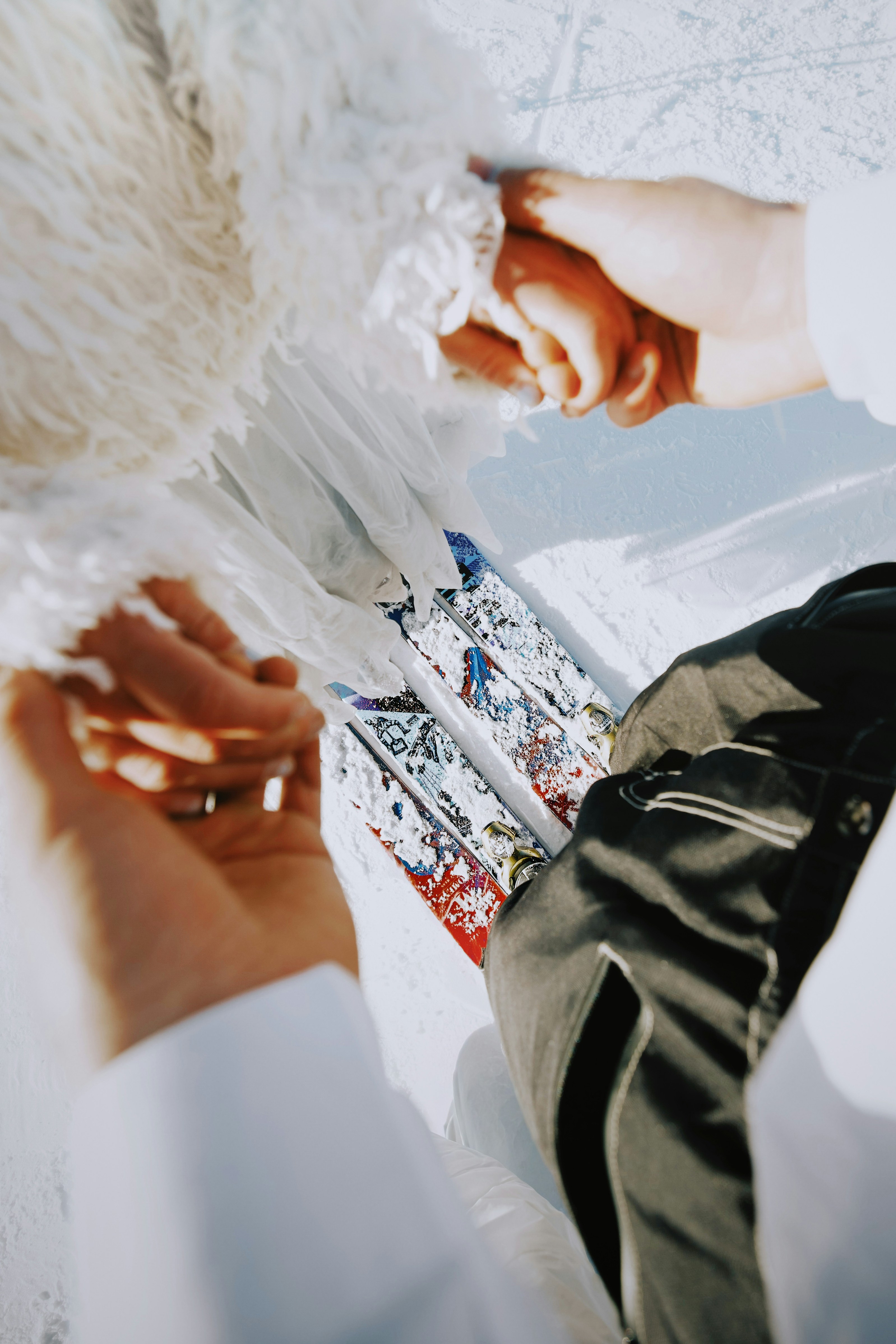 Two people holding hands on a snowy surface.