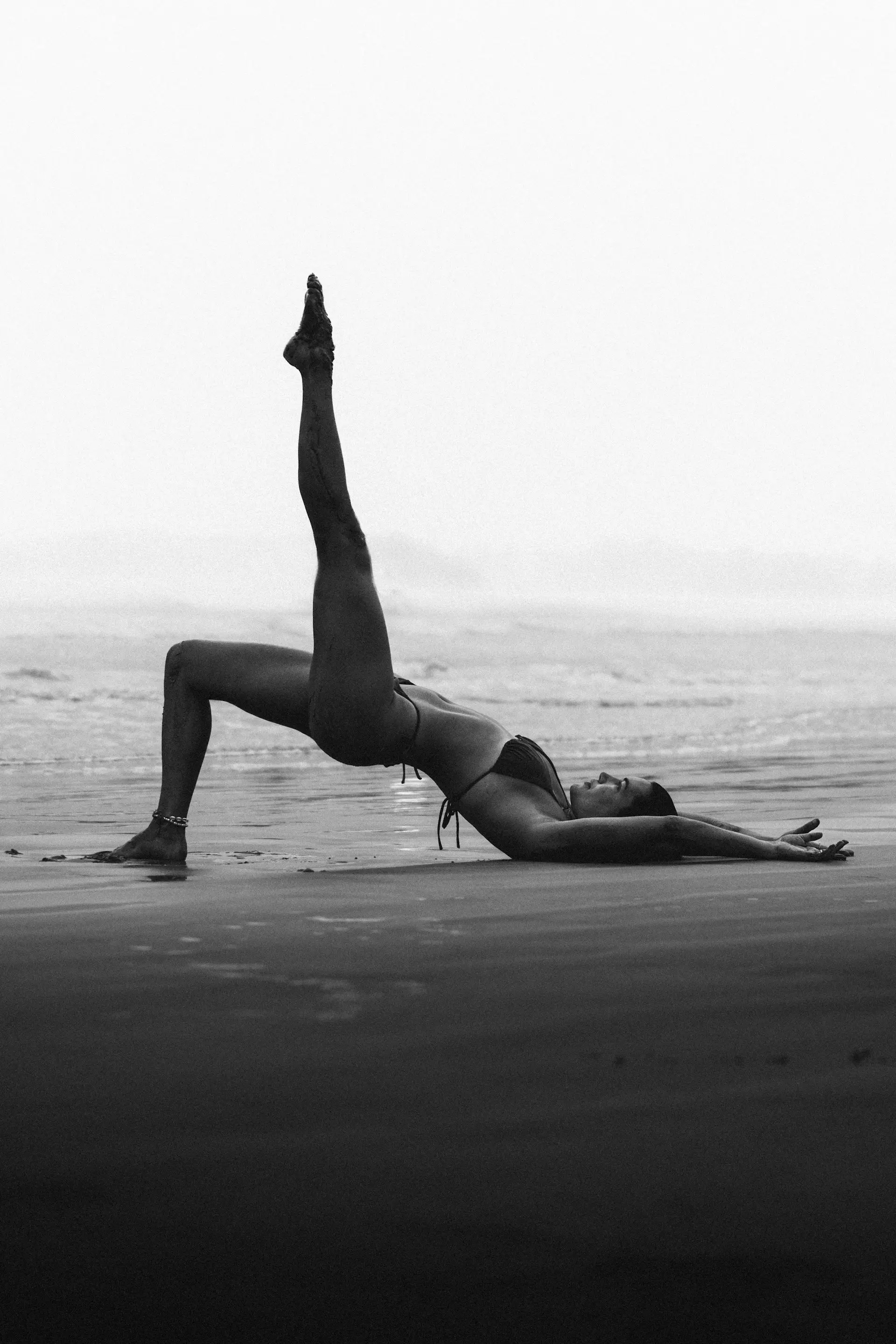 Woman practicing yoga on the beach during a NUA retreat in Bali.