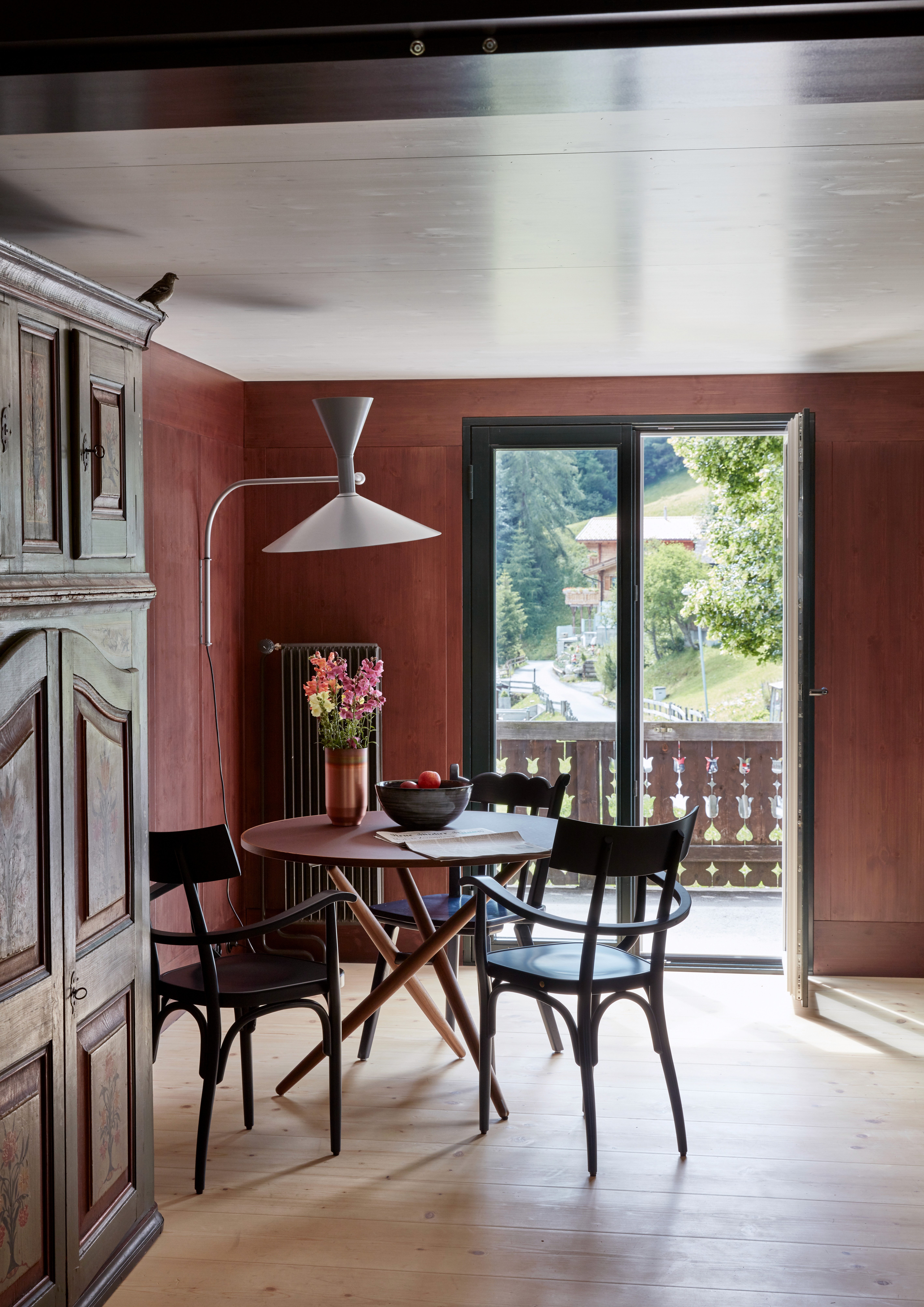 A round dining table next to an old wooden cupboard.