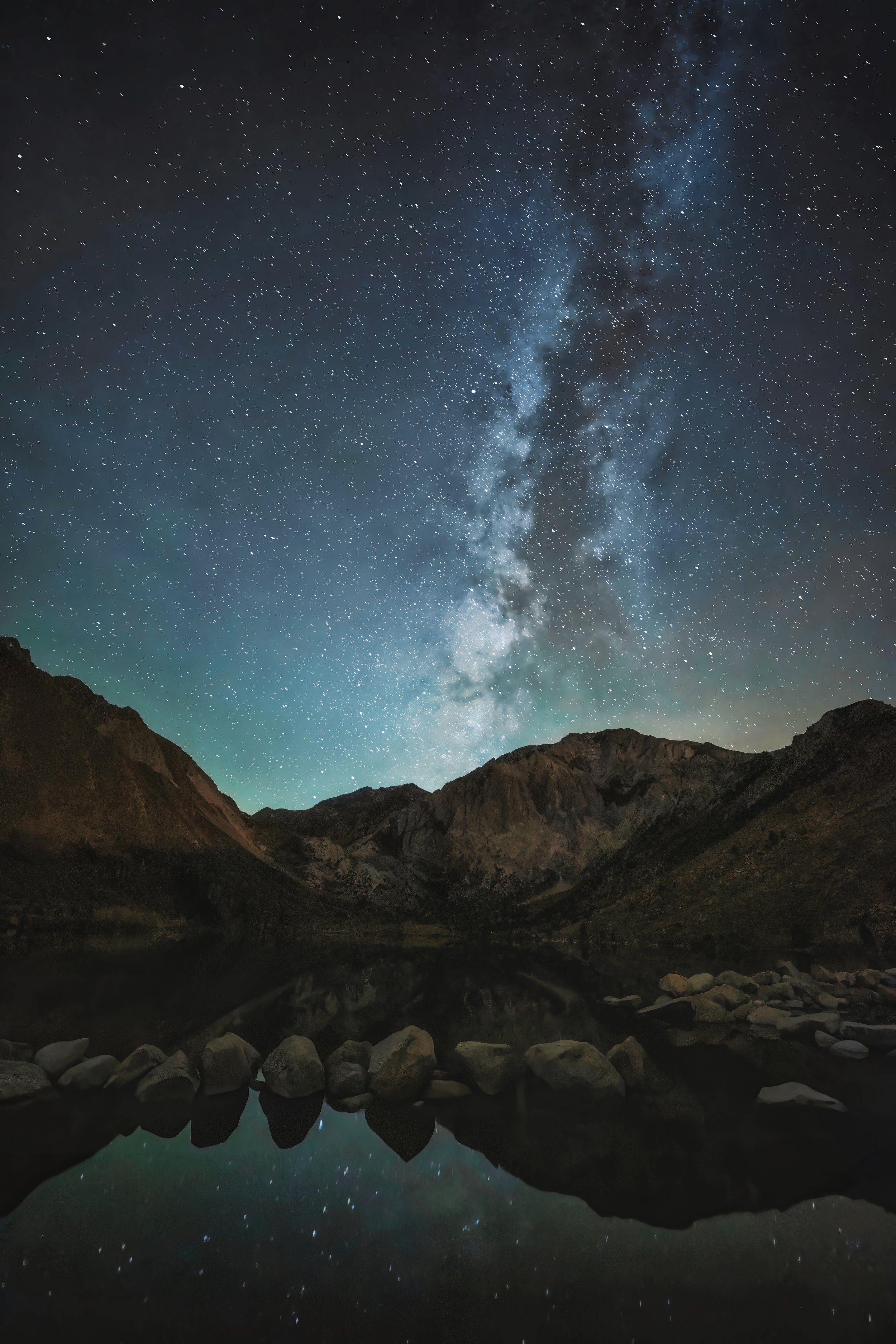 Milky Way rising over mountains, reflected in a still alpine lake