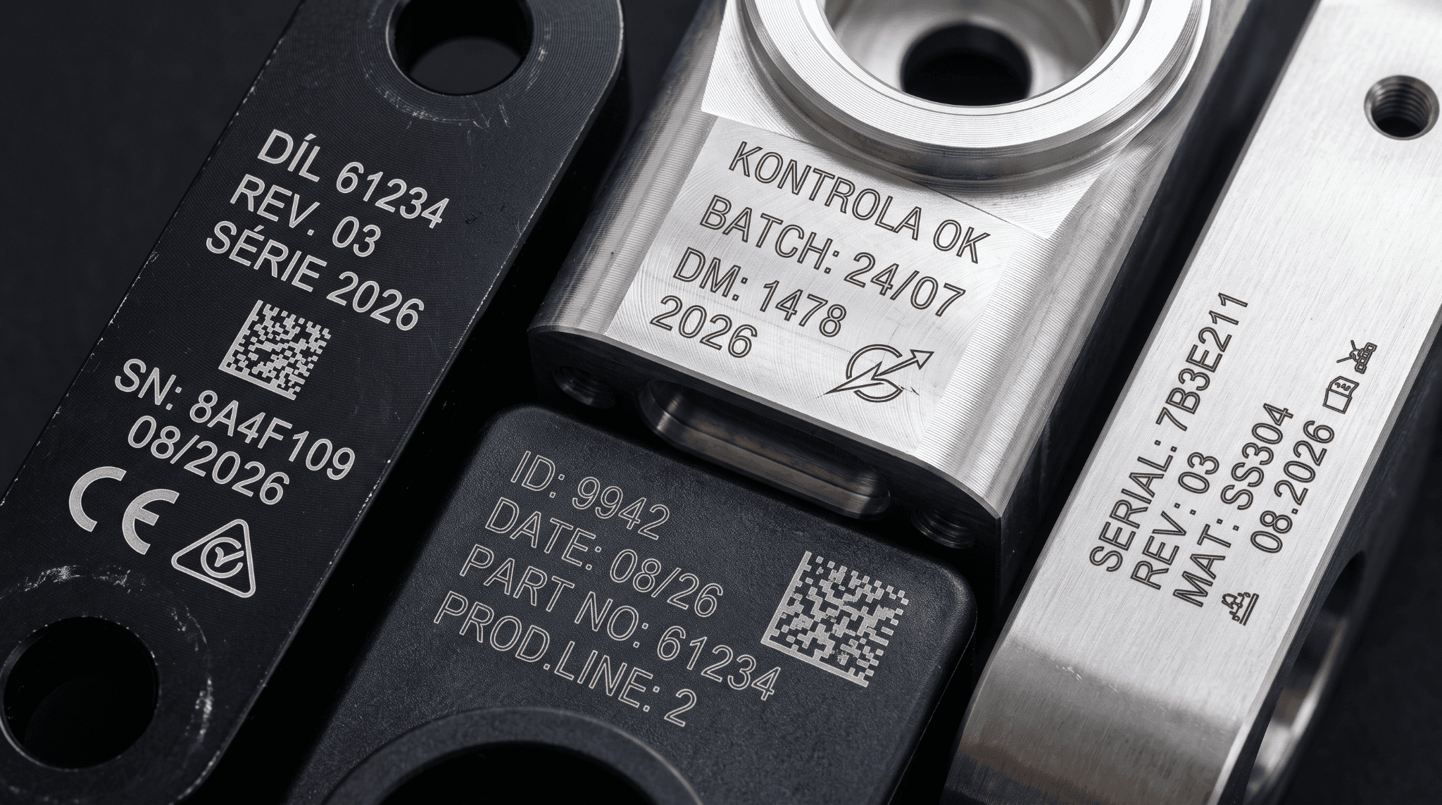 Detail černých a stříbrných součástek s vyznačenými názvy, čísly a QR kódy