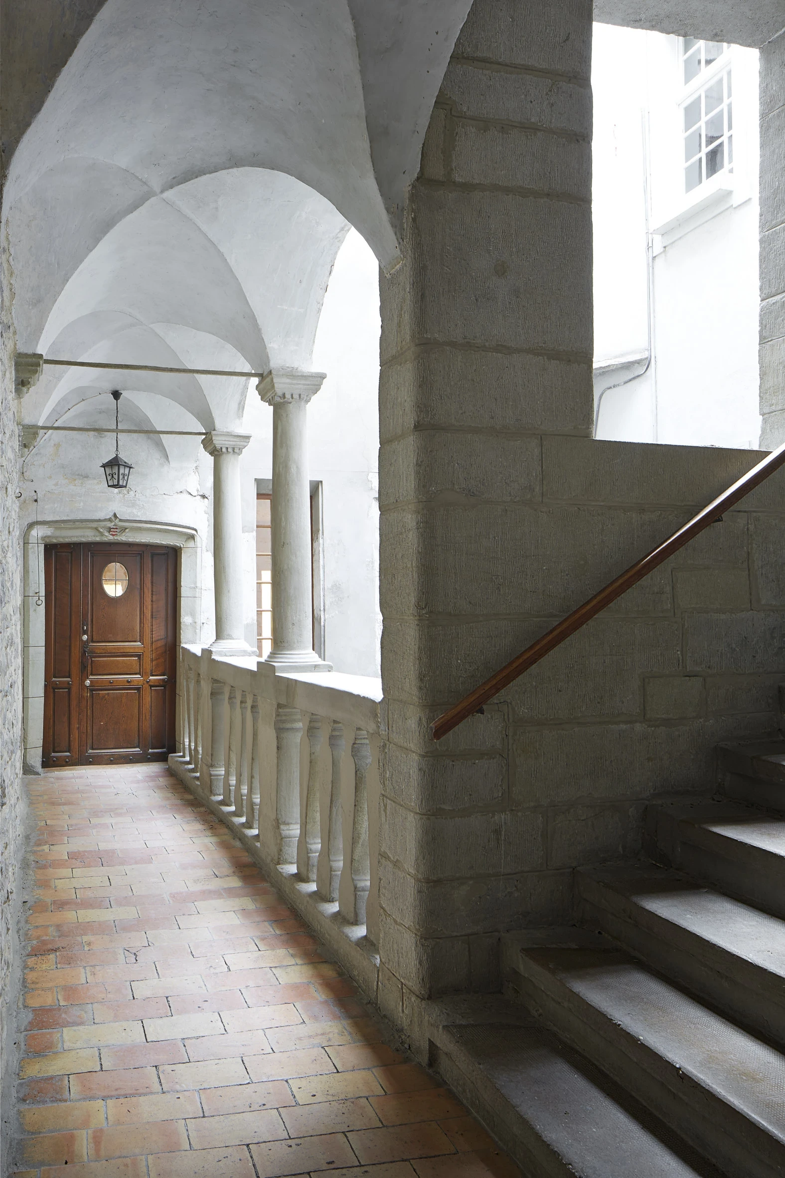 Galerie du XVIIIᵉ siècle de la maison Vernet à Morges, avec sol en tommettes, voûtes croisées, colonnes sculptées en molasse et encadrement de porte gothique.