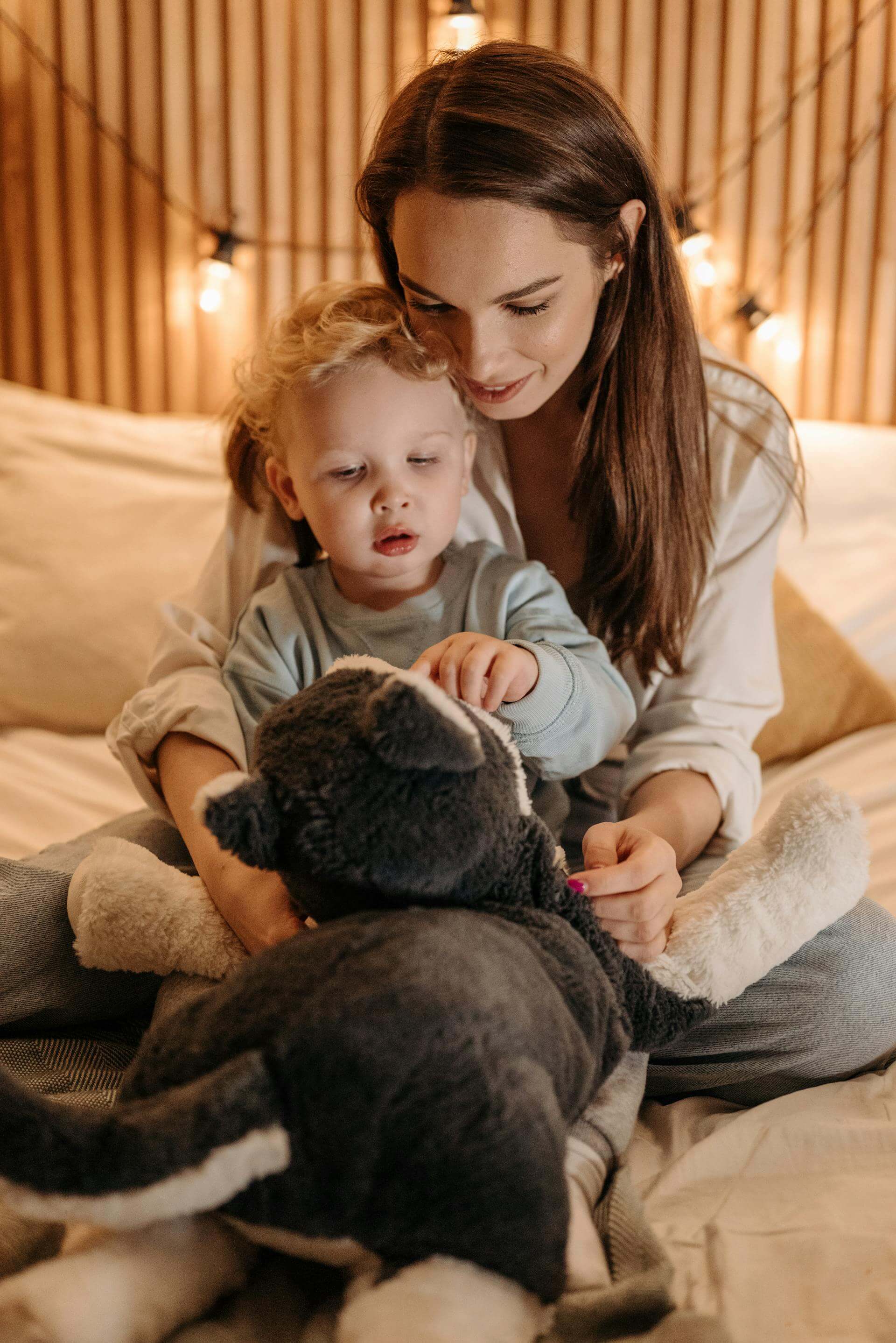 A joyful woman and child playing together with a colorful stuffed animal, sharing smiles and laughter