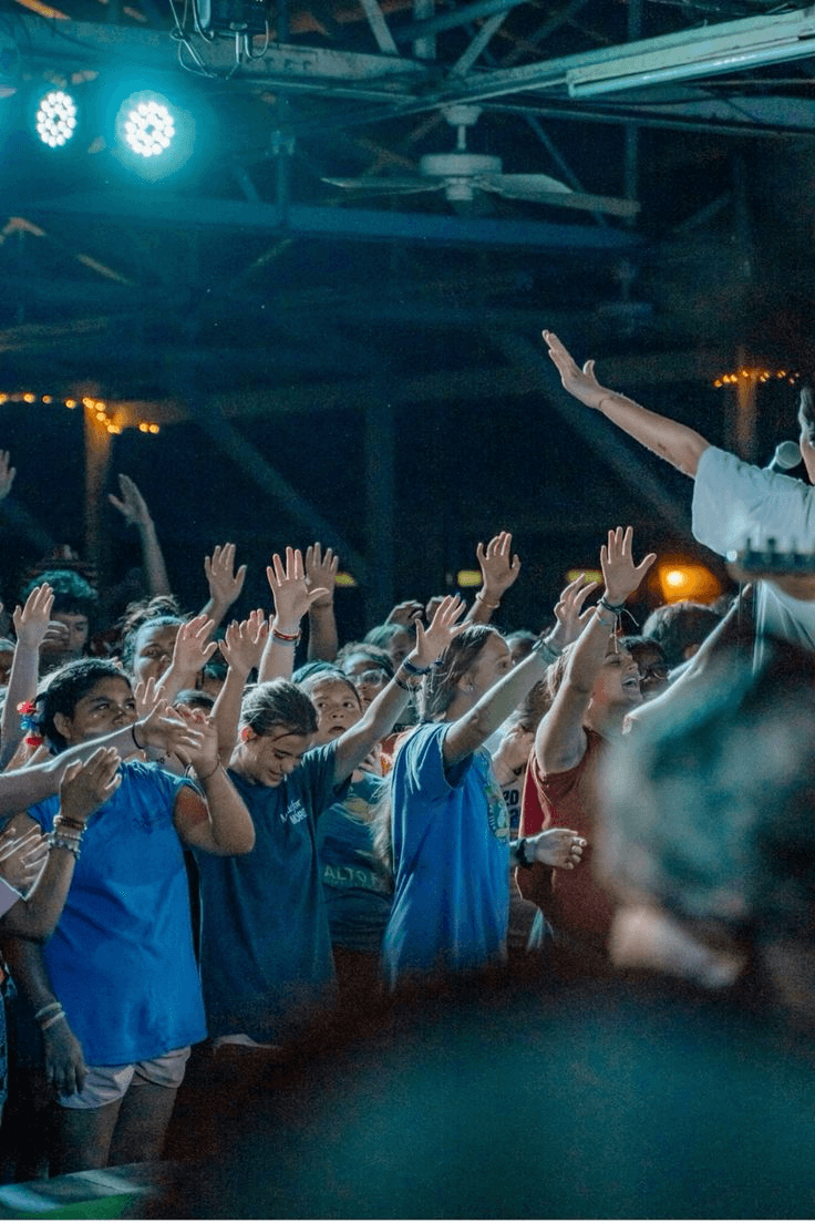Close-up portrait of a person wearing a gray insulated hooded jacket with the hood up, showing their face framed by the hood against a light background.