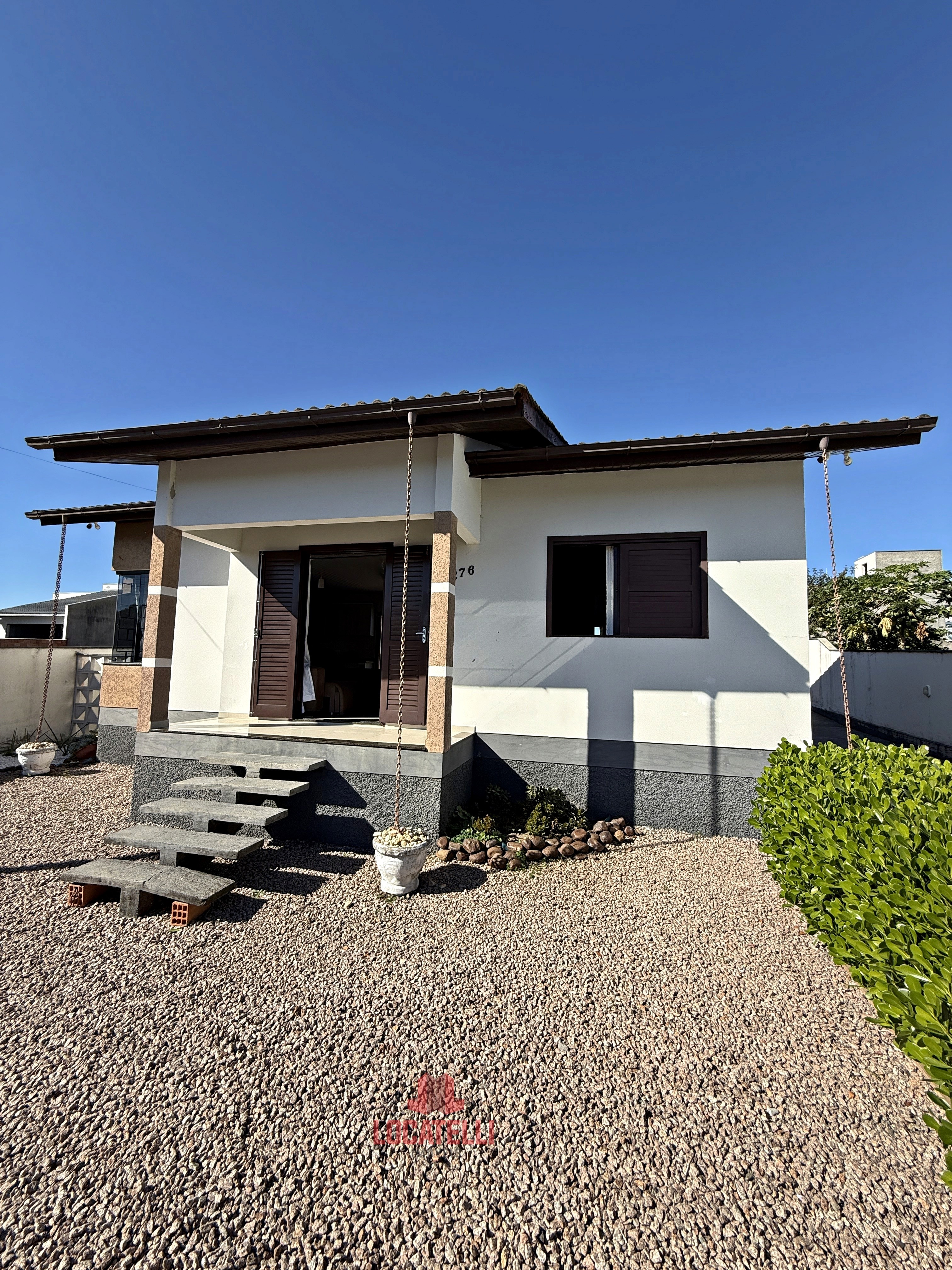 A modern brick house with a two-car garage, well-manicured lawn, and clear blue sky in the background.