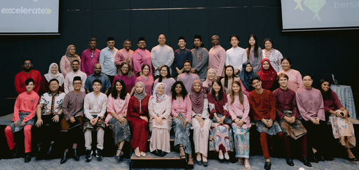 A diverse group of individuals in traditional attire poses together on a staircase, smiling in a modern interior setting.