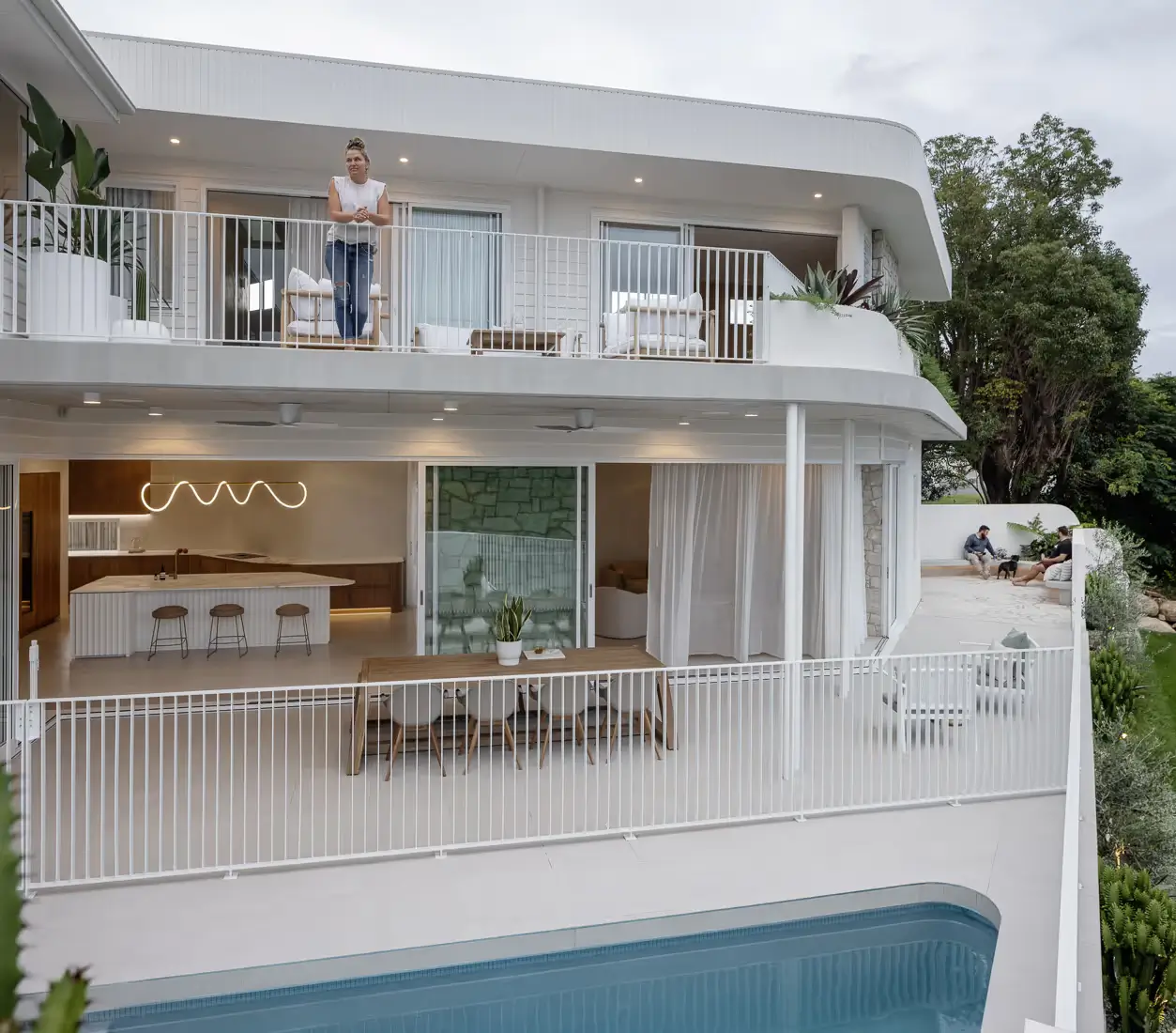 A woman standing on a verandah overlooking a pool.