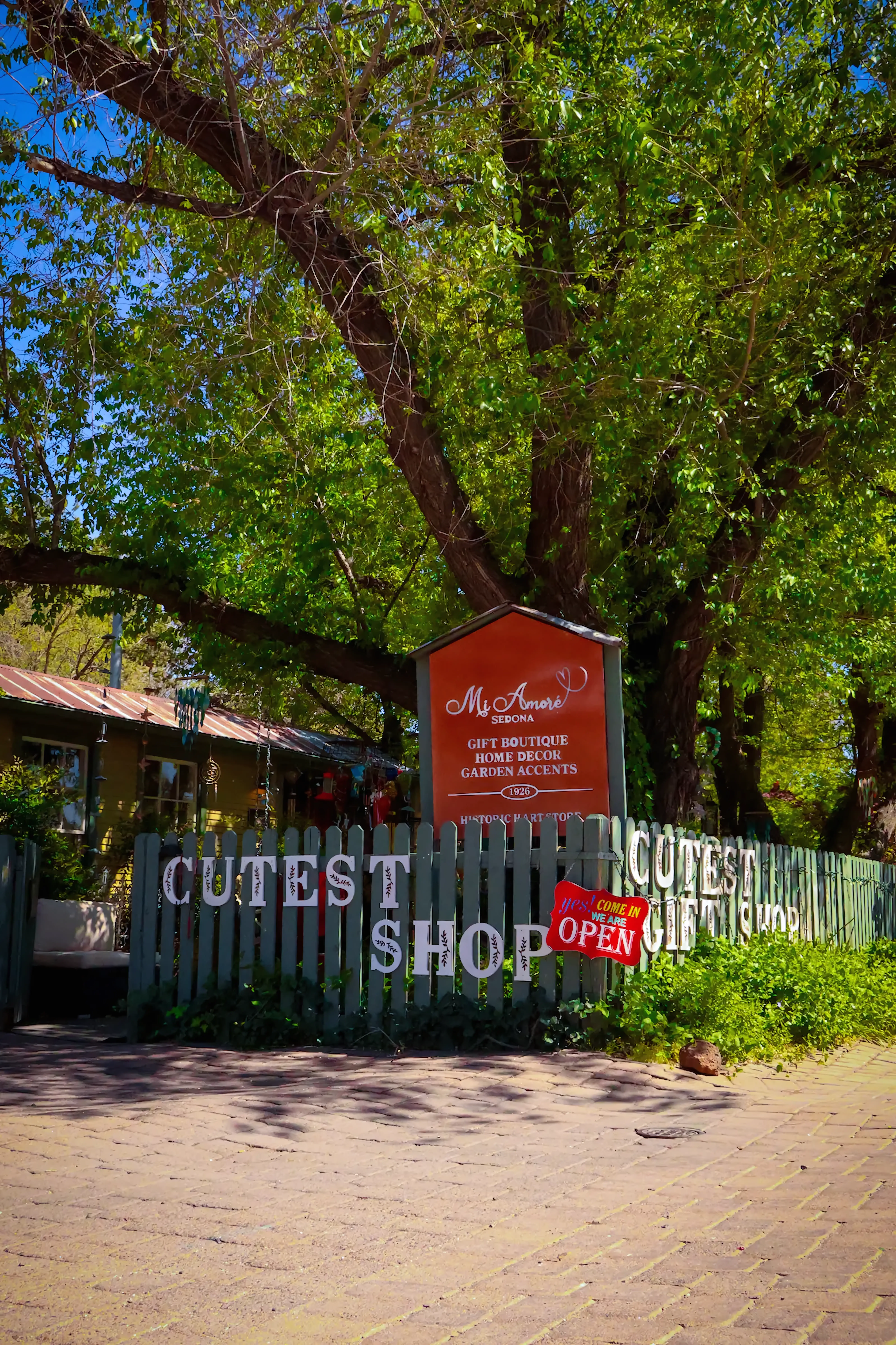 Front of Mi Amore Sedona gift shop in Sedona Arizona, featuring historic Hart Store signage, lush garden setting, and ‘Cutest Gift Shop’ display at the entrance