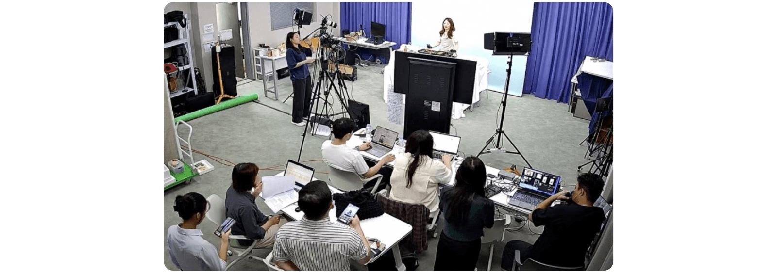 라이브 방송 스튜디오에서 쇼호스트가 진행하는 동안 운영팀이 노트북으로 채팅과 주문을 실시간으로 모니터링하는 모습