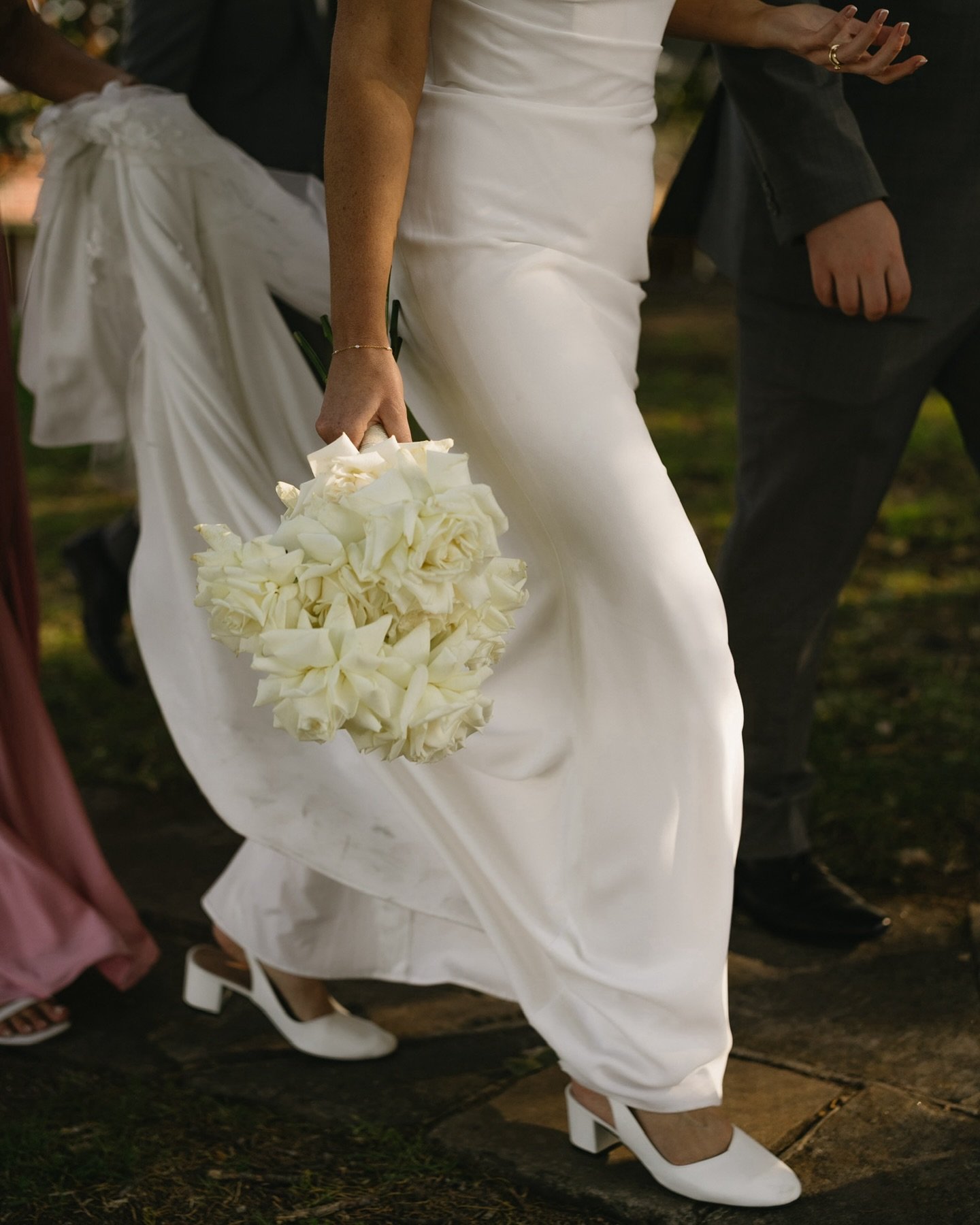 Bride walking with a white bouquet during an outdoor wedding ceremony