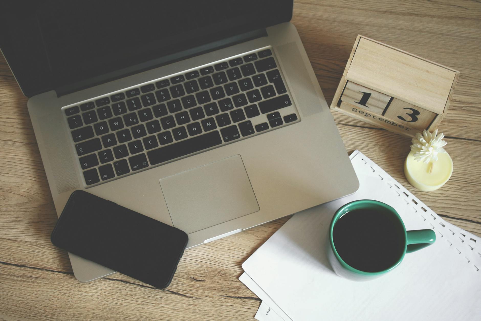 An overhead view of a clean wooden desk with an open planner, a coffee mug, and a pen ready for lesson planning.