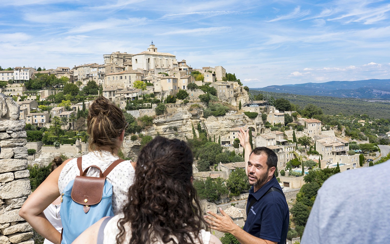 Tour guide explaining the view of Gordes village in Provence to visitors.