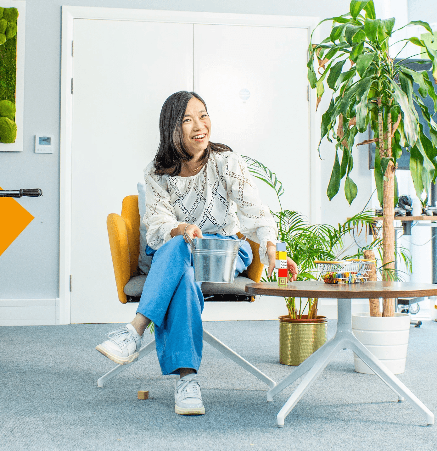 Young woman smiling sat at a table in a bright, modern office