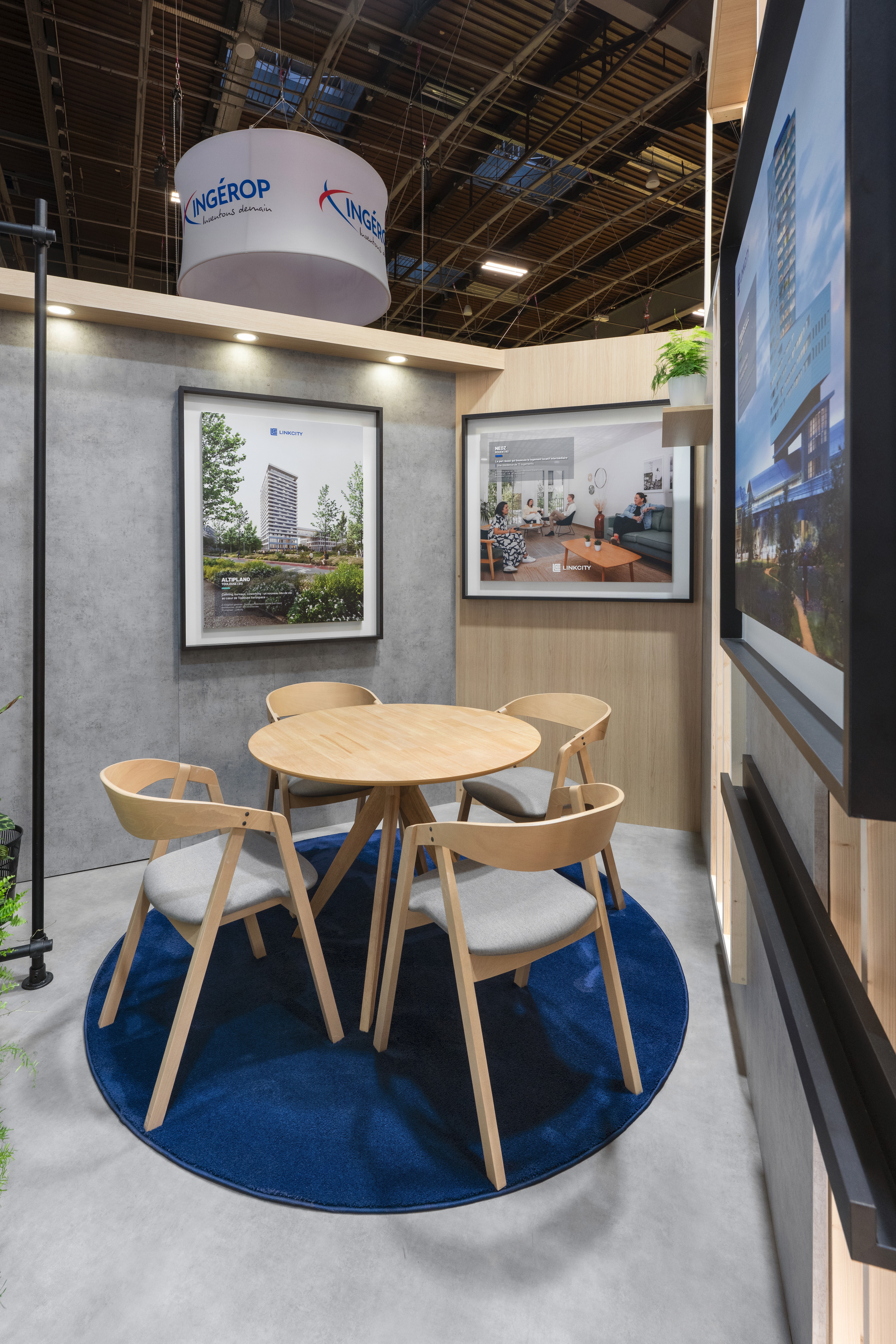 Stand Groupe Bouygues SIMI 2025 Paris par Expace – détail espace lounge avec table ronde bois, chaises design et visuel projet immobilier encadré mural
